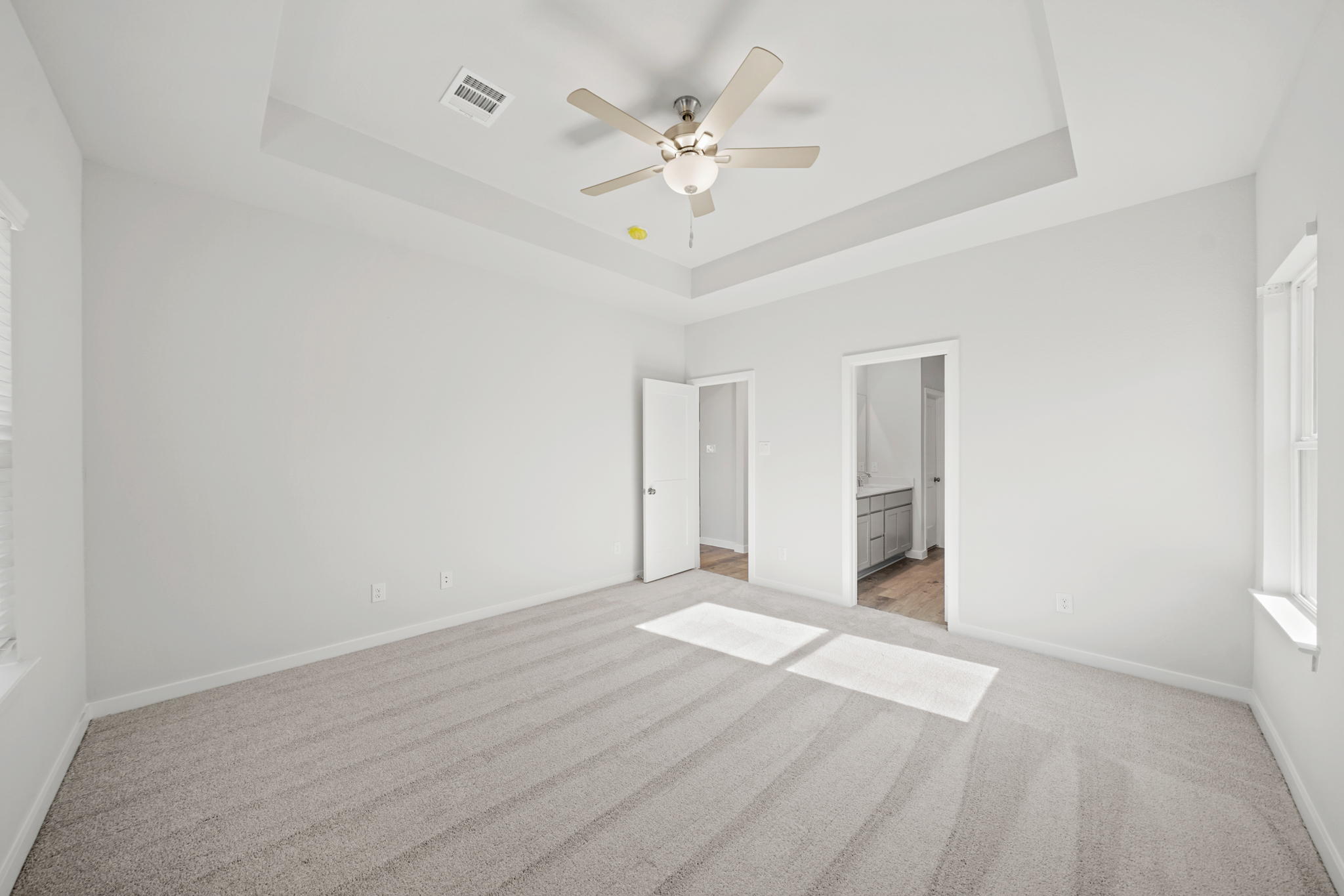A room with a ceiling fan and a carpet.
