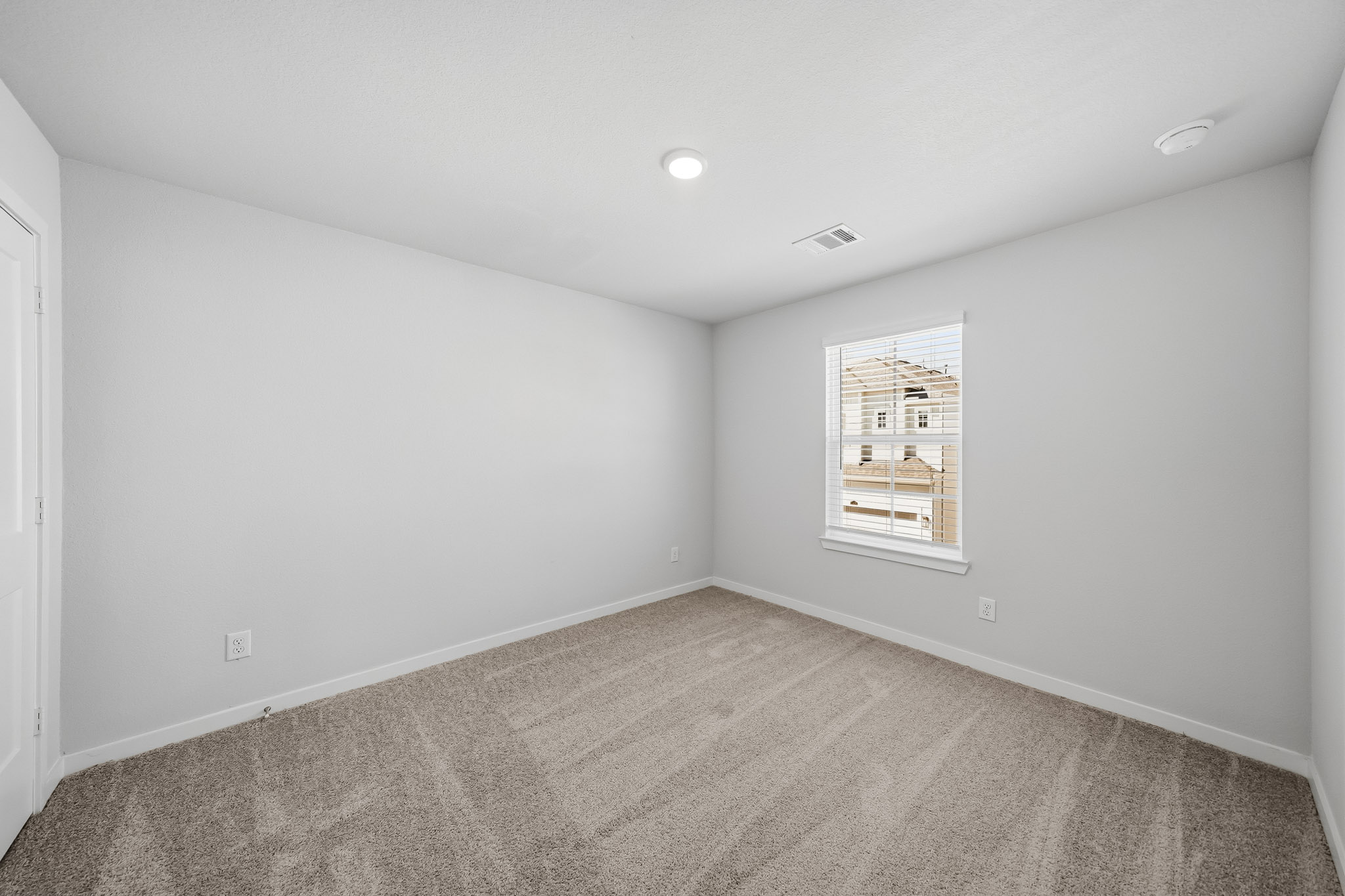 A room with a carpet and a white wall.