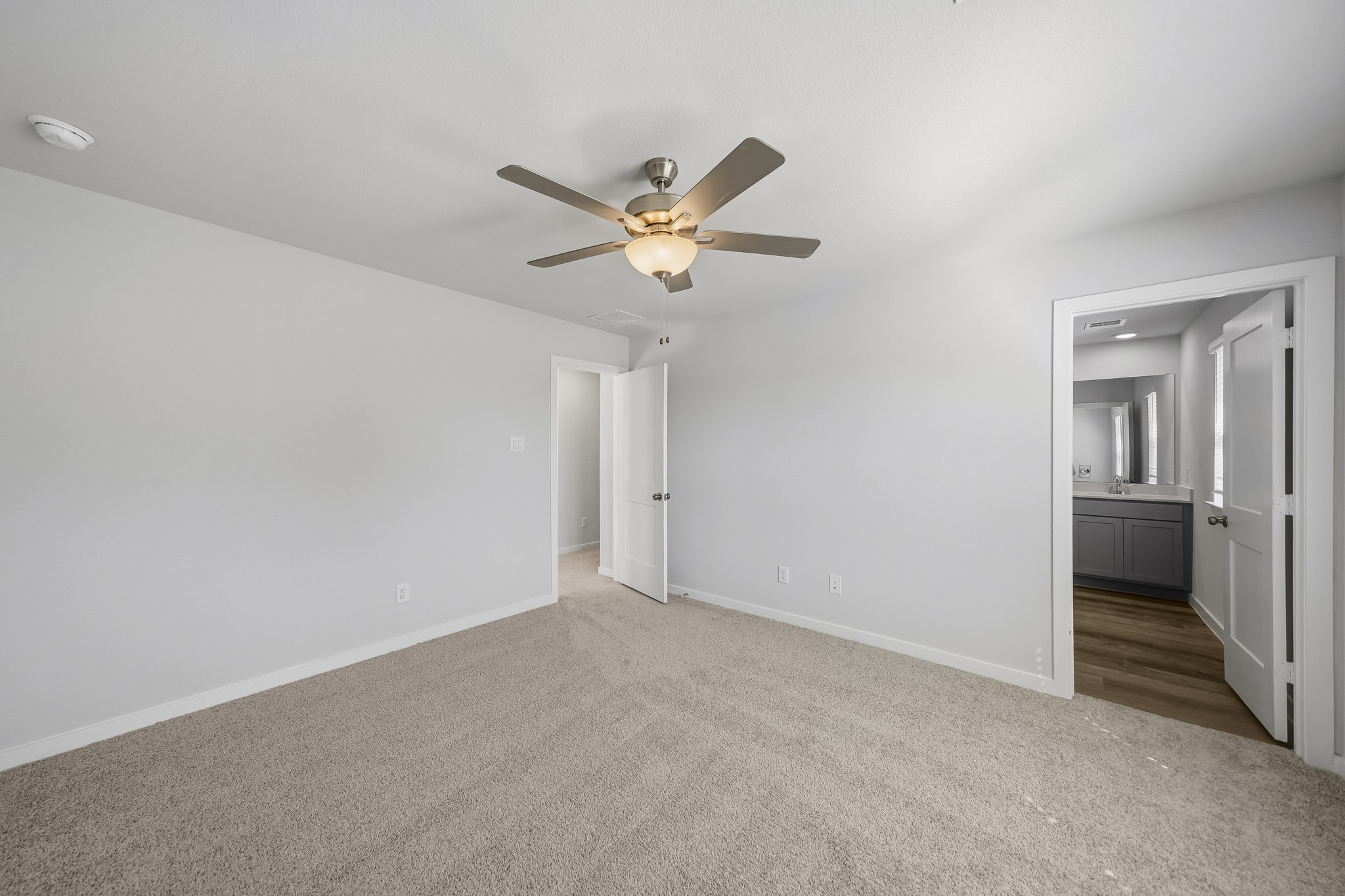A room with a ceiling fan and white walls.