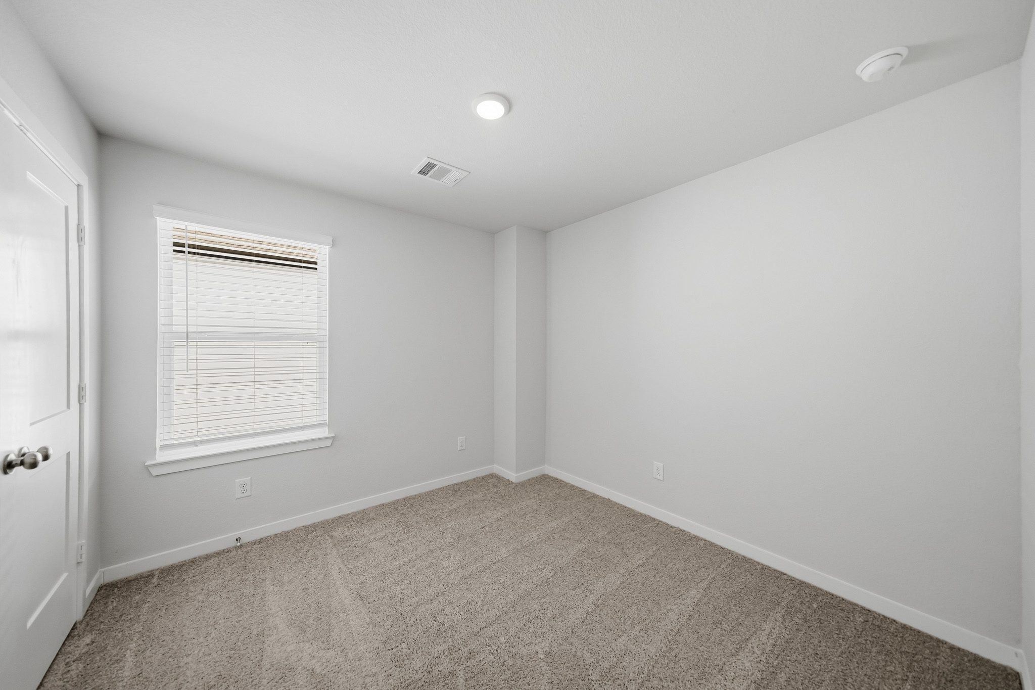 A room with a carpet and a door.
