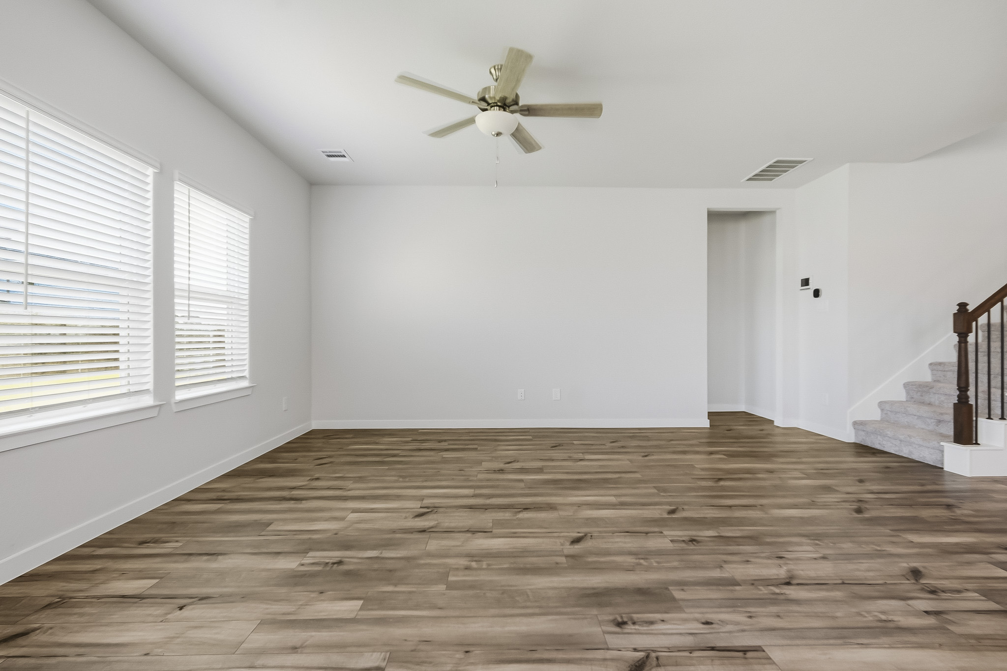 A room with a wood floor and a ceiling fan.