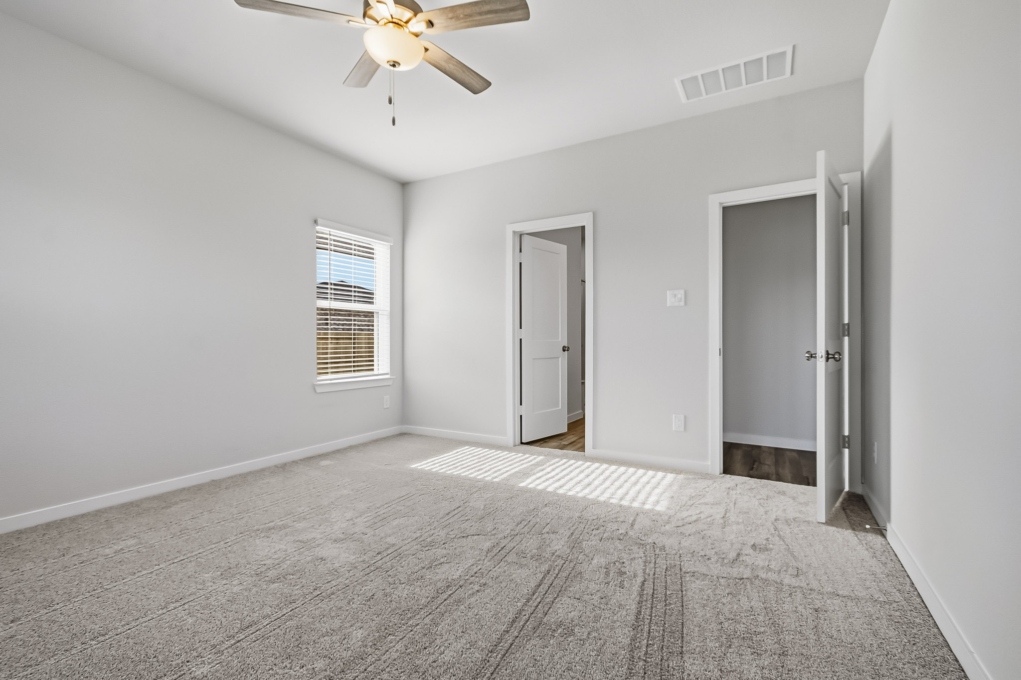 A room with a ceiling fan and a carpet.