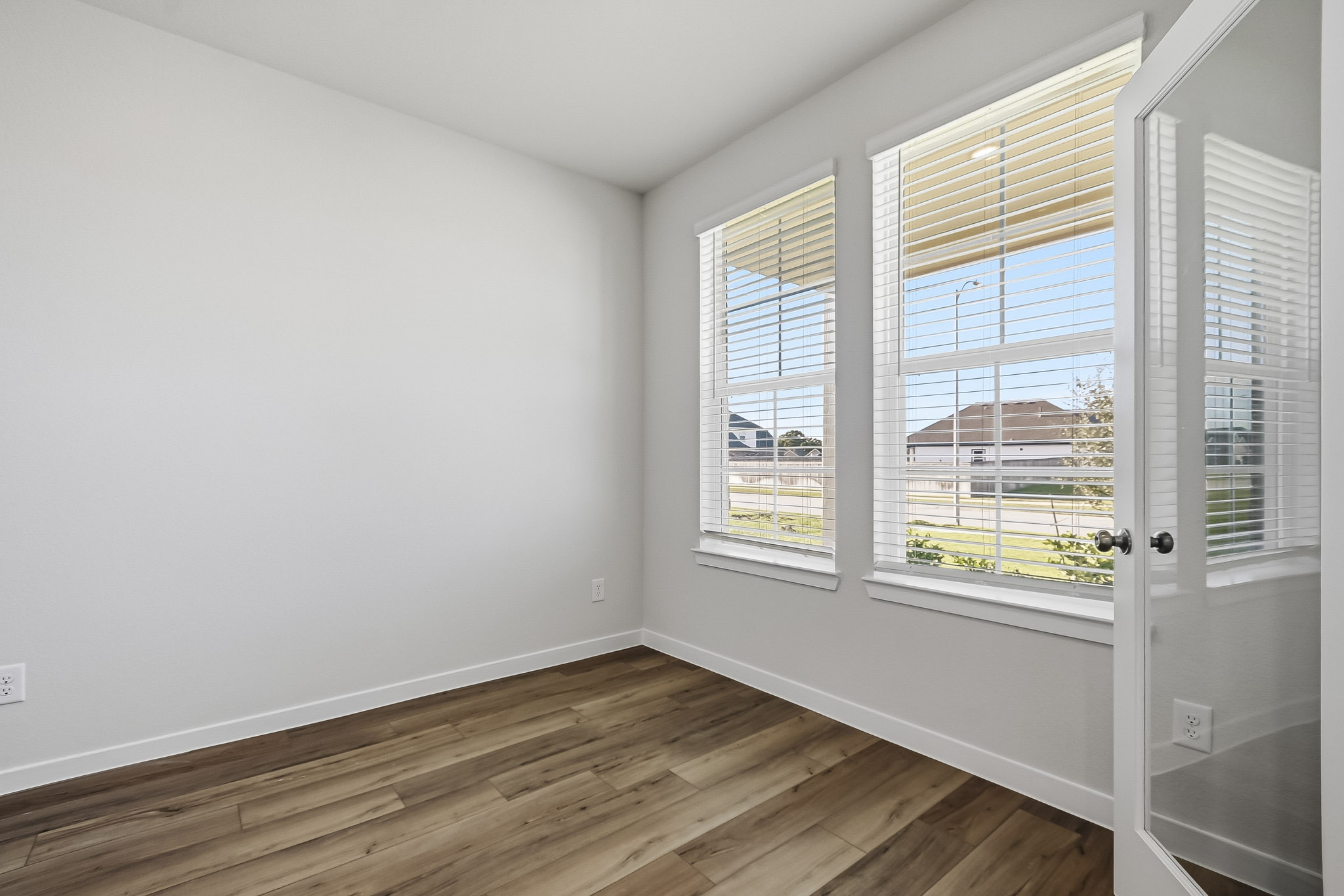 A room with windows and a wood floor.