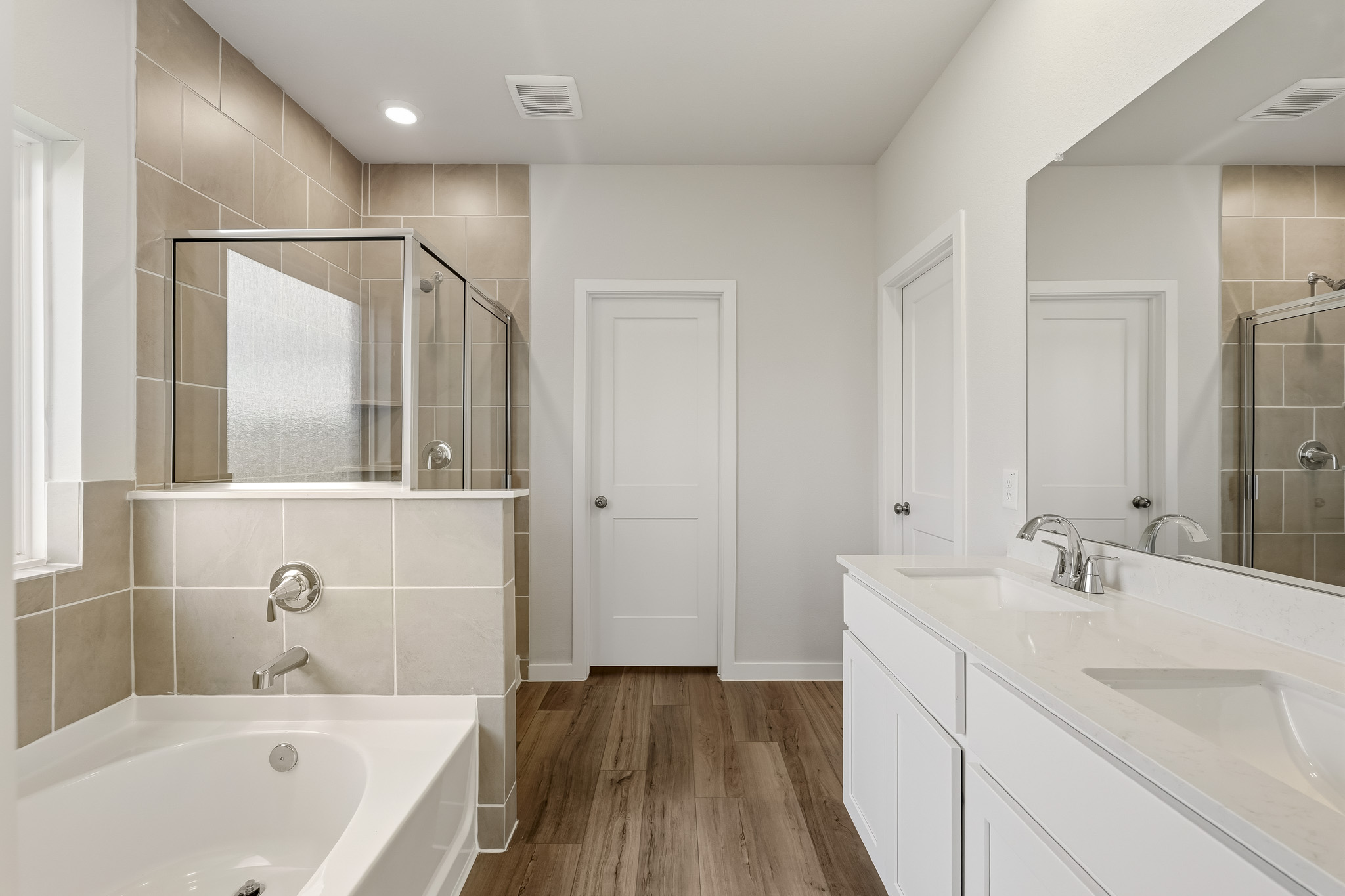 A bathroom with a tub sink and mirror.