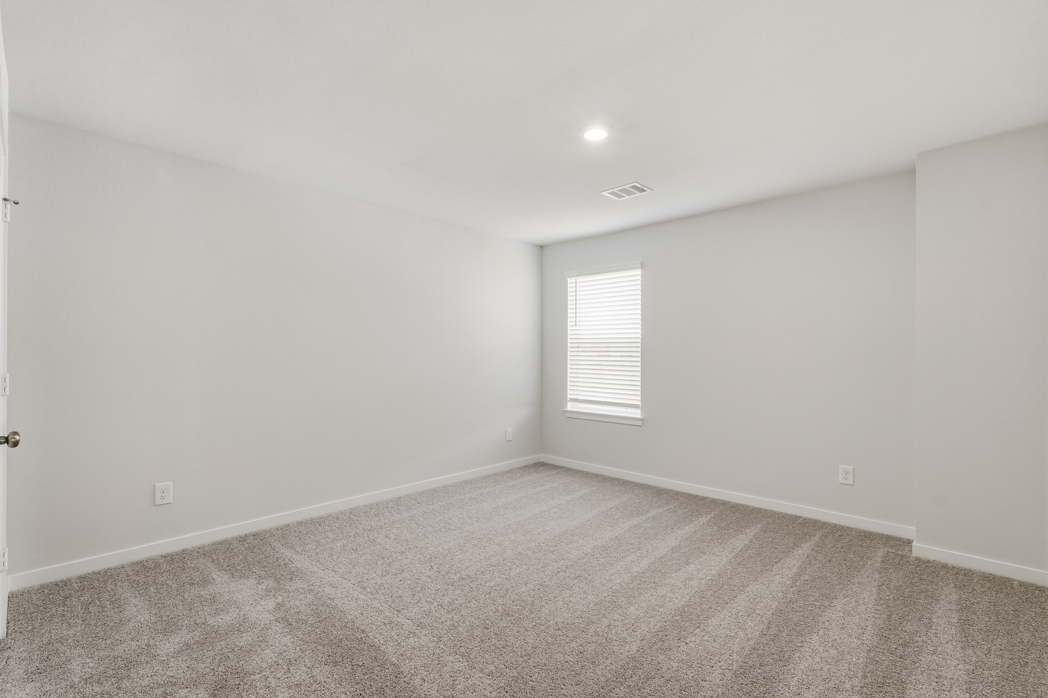 A room with a carpet and a window.
