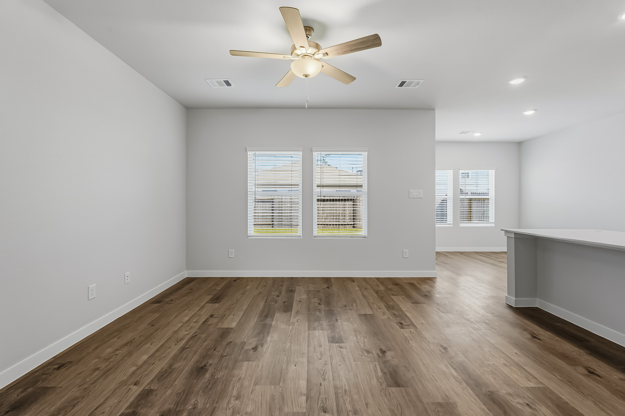 A room with a ceiling fan and a wood floor.