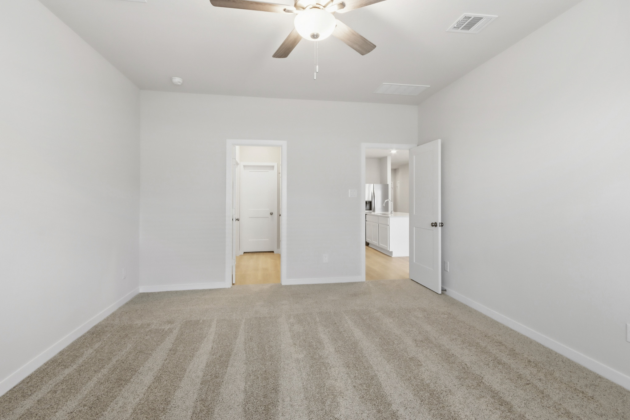 A room with a ceiling fan and a door.