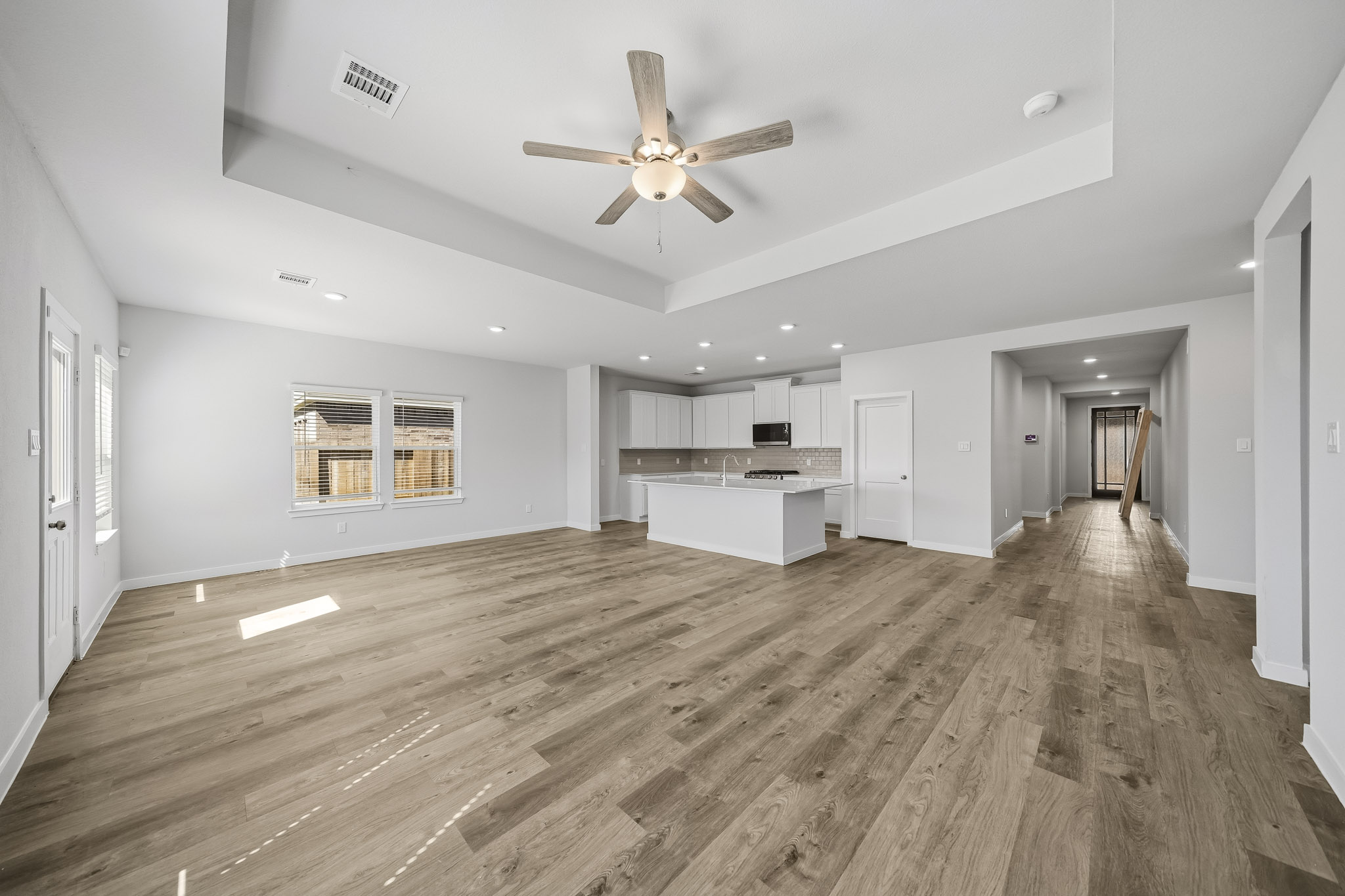 A large empty room with a wood floor and a ceiling fan.