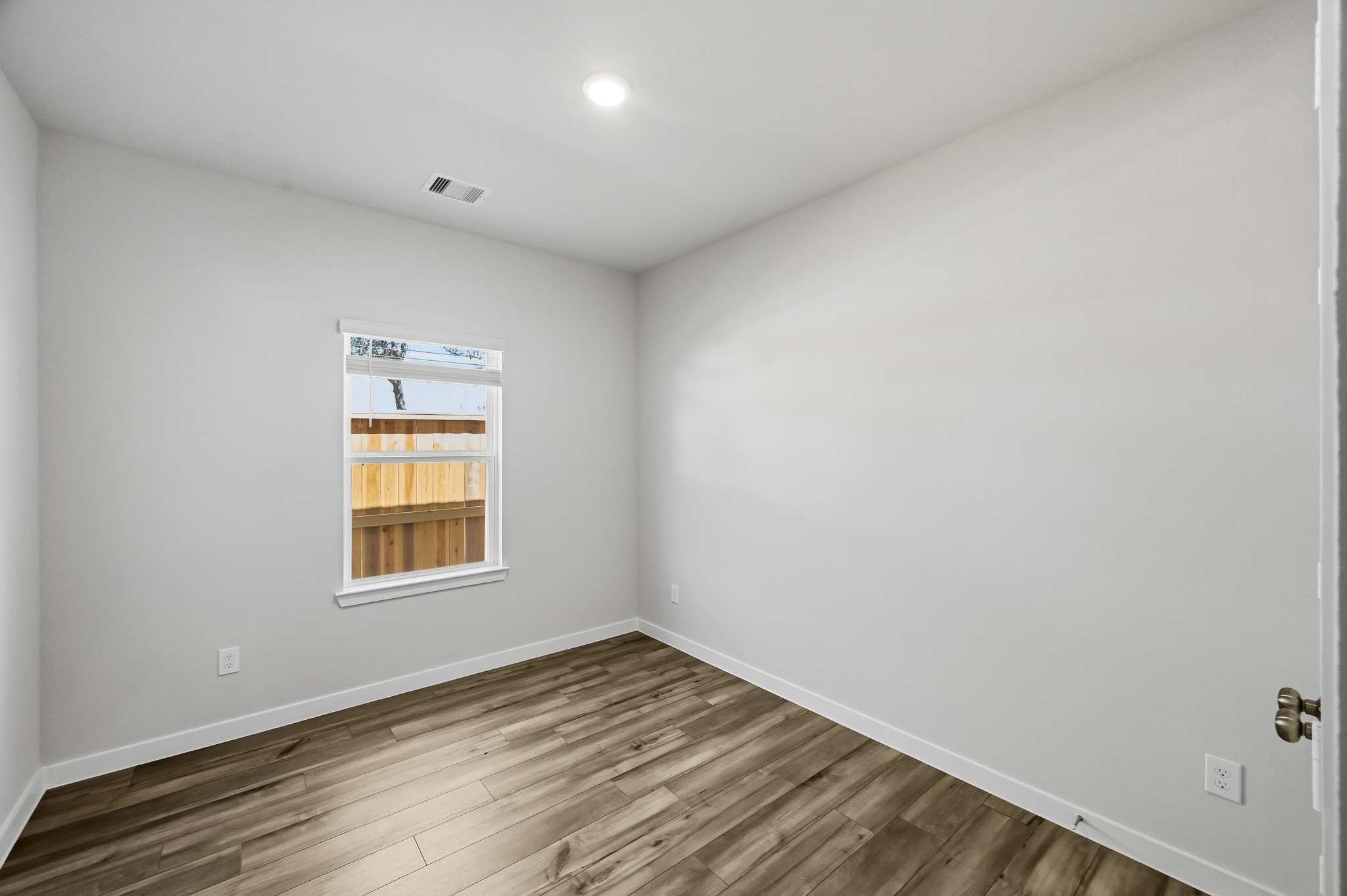 A room with a wood floor and a window.