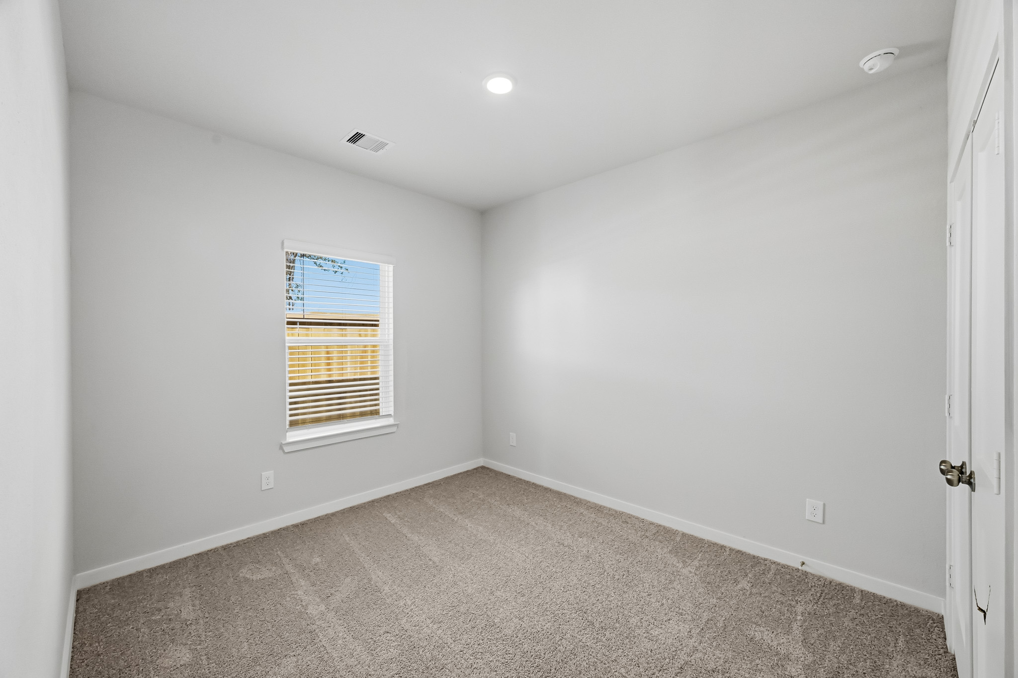 A room with a window and carpet.