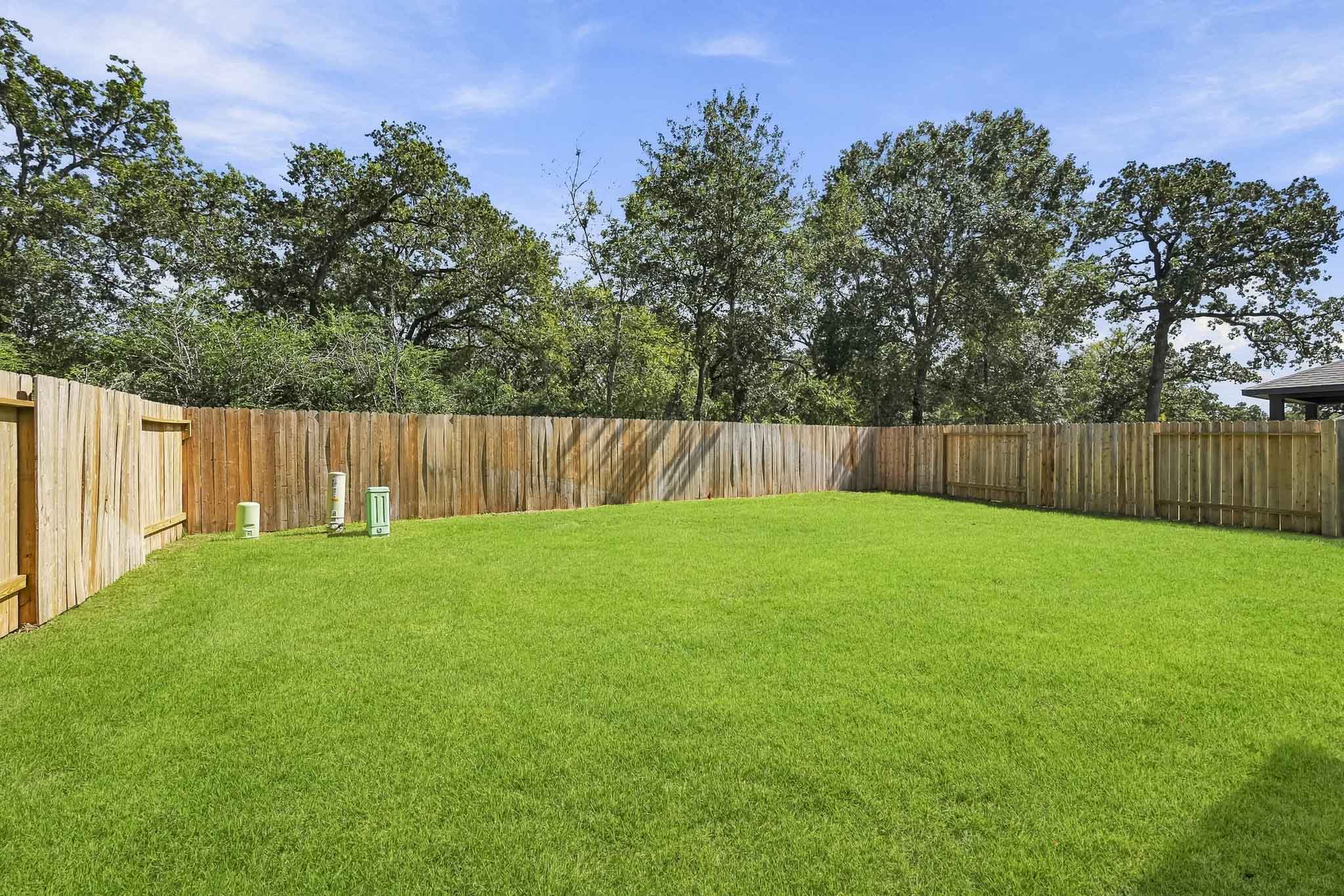 A fenced in yard with trees.