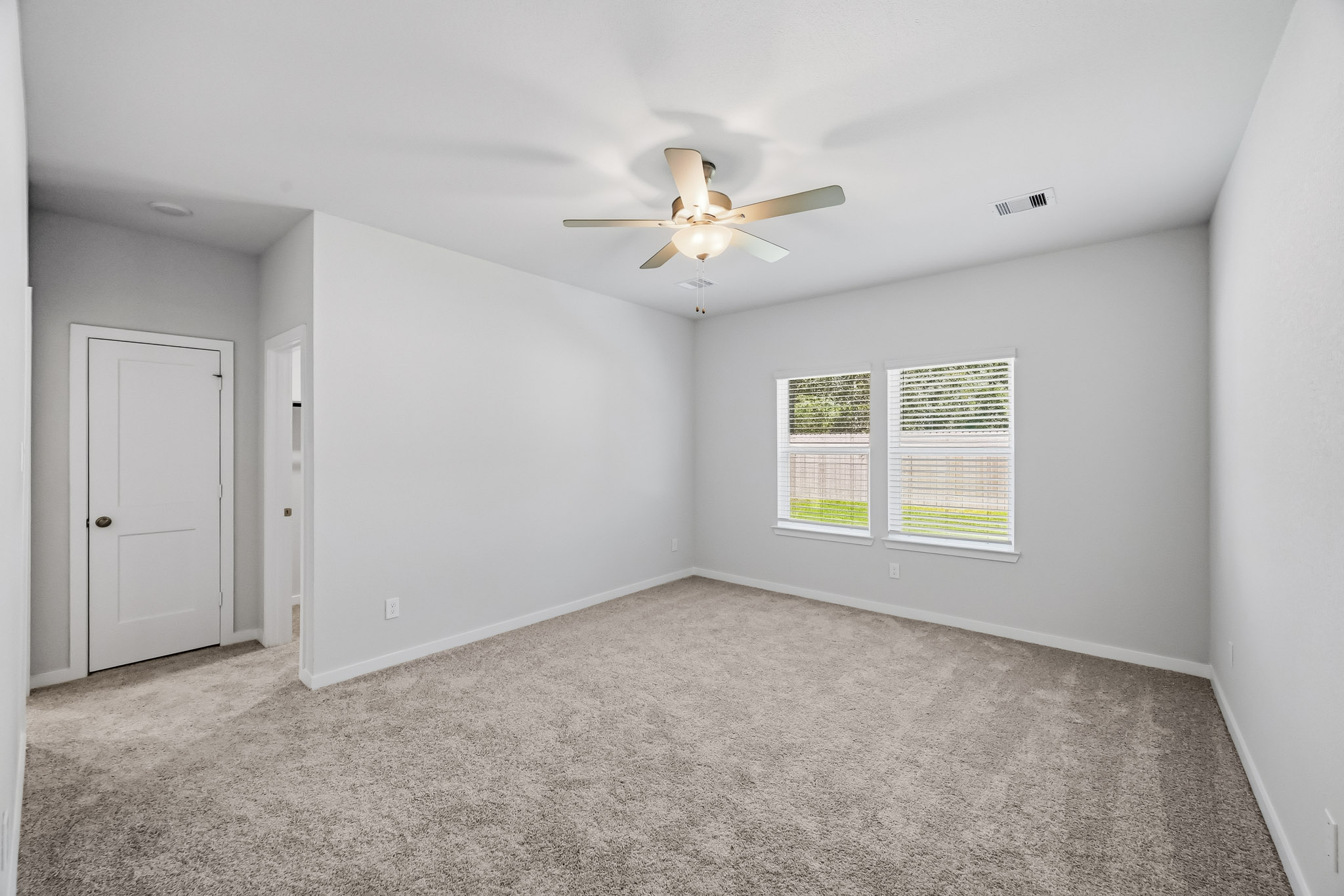 A room with a ceiling fan and a door.