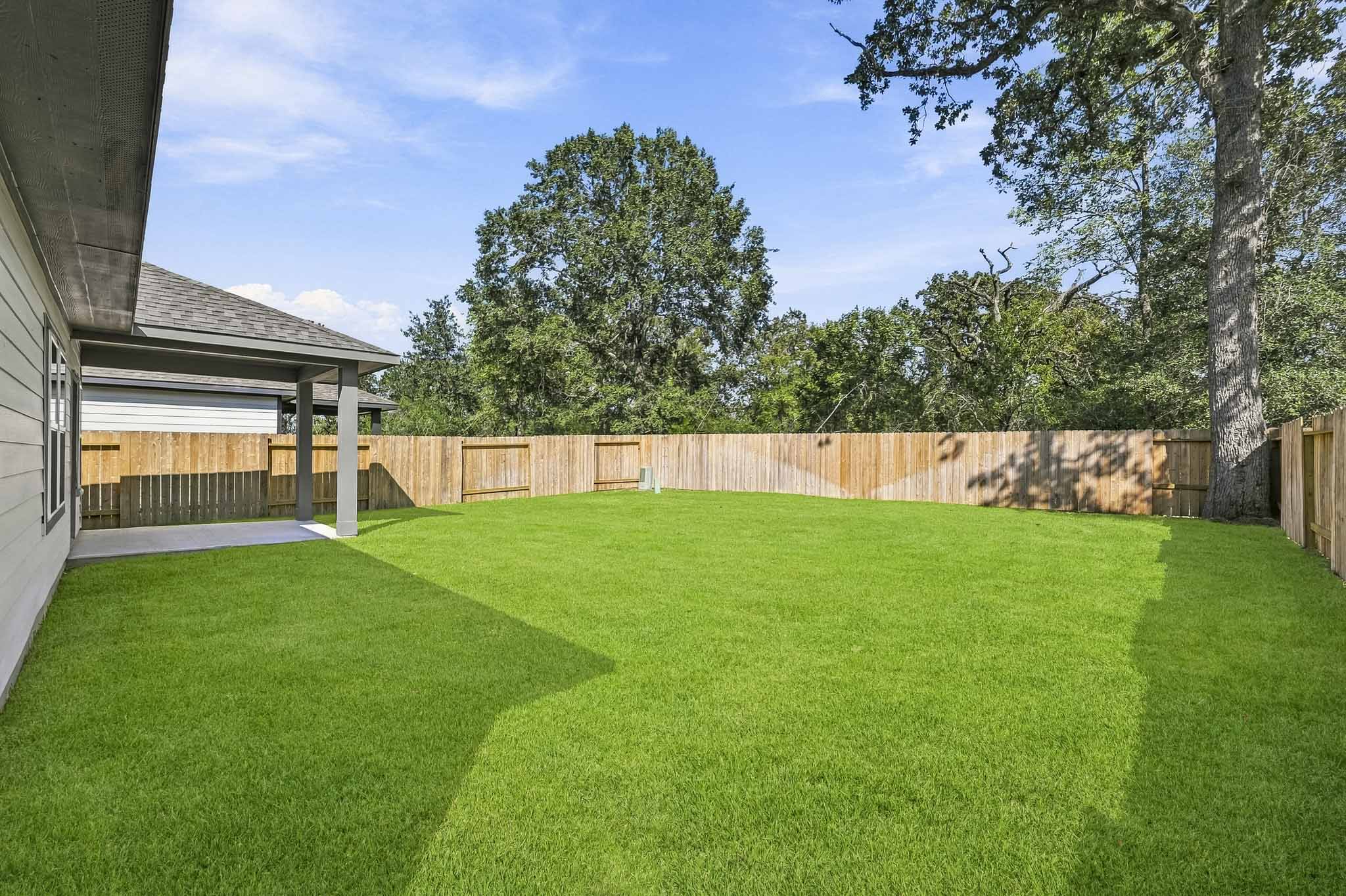A backyard with a fence and trees.