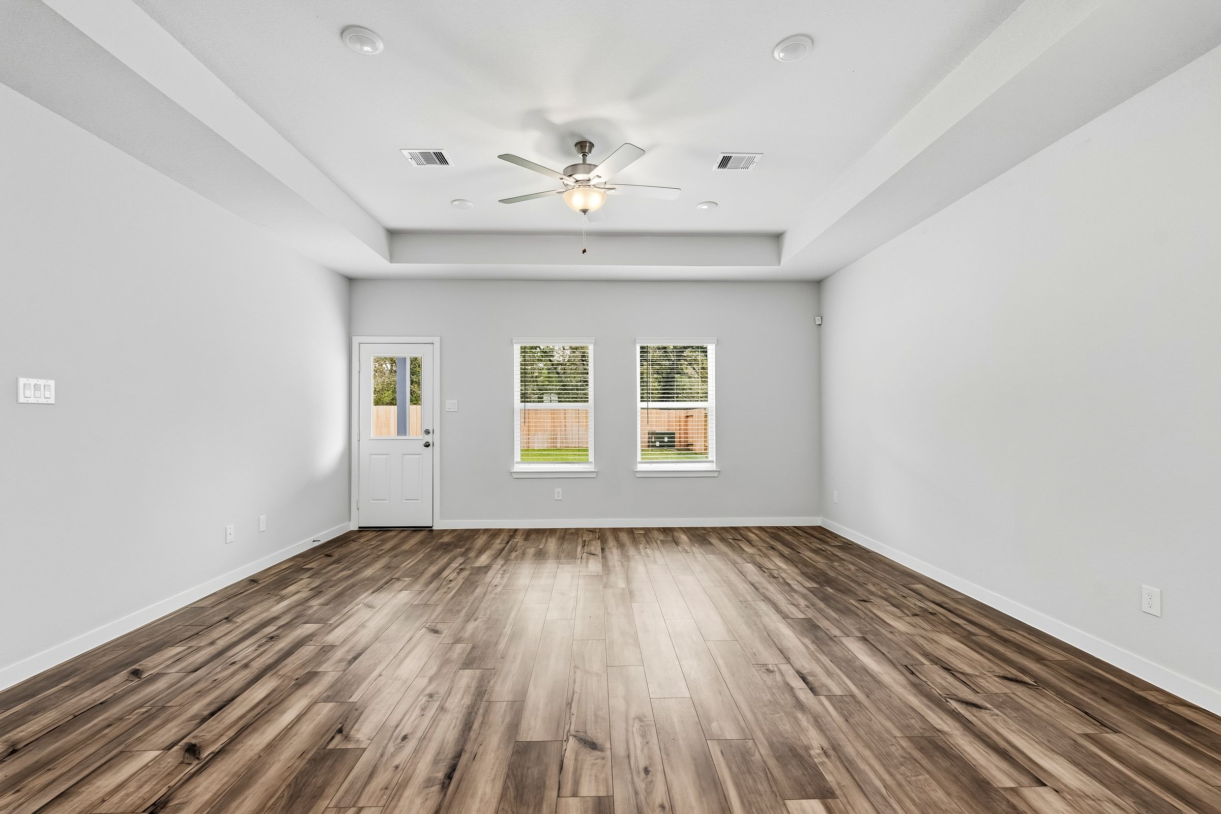 A room with a wood floor and a ceiling fan.