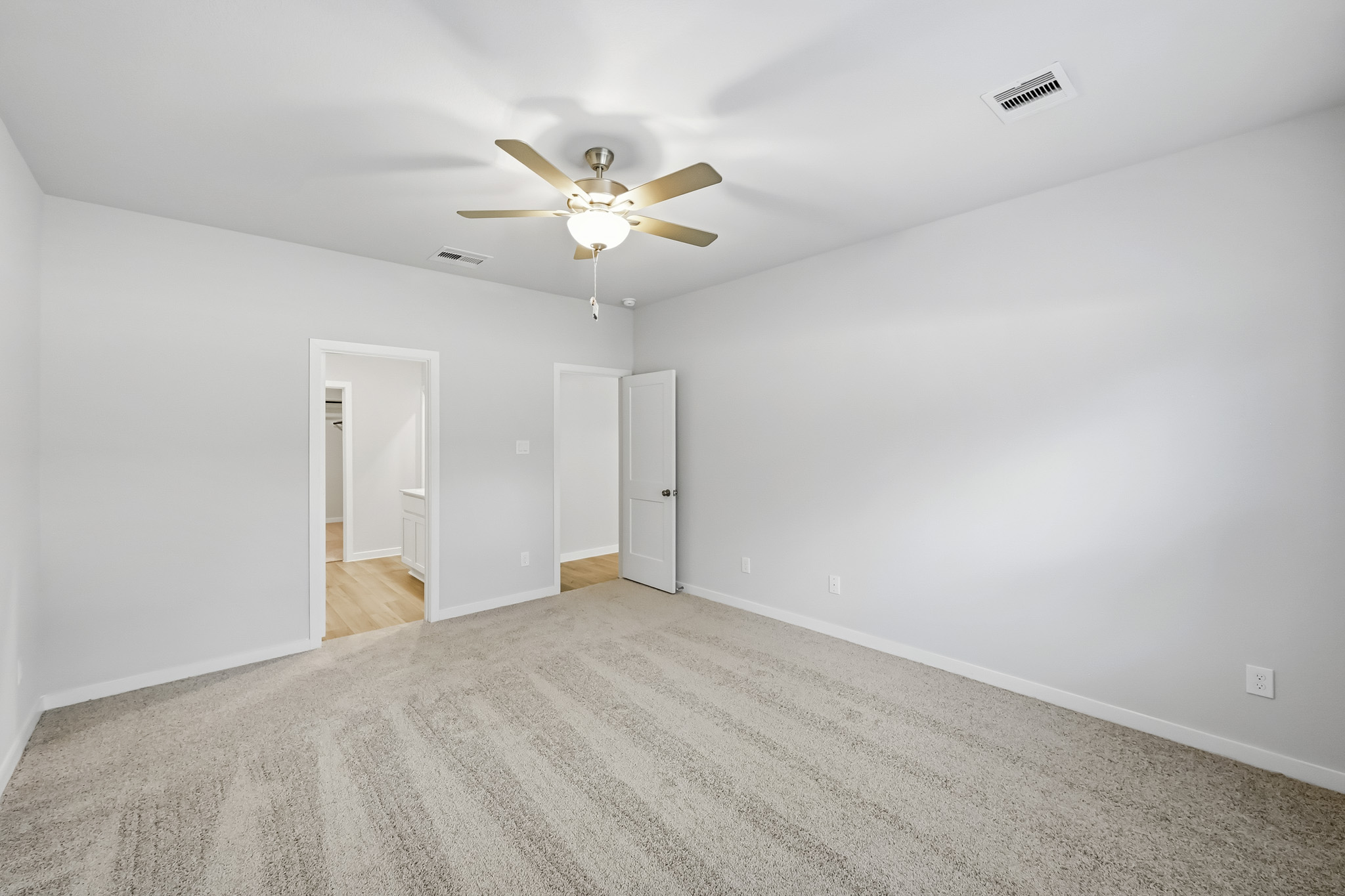 A room with a ceiling fan and a carpet.