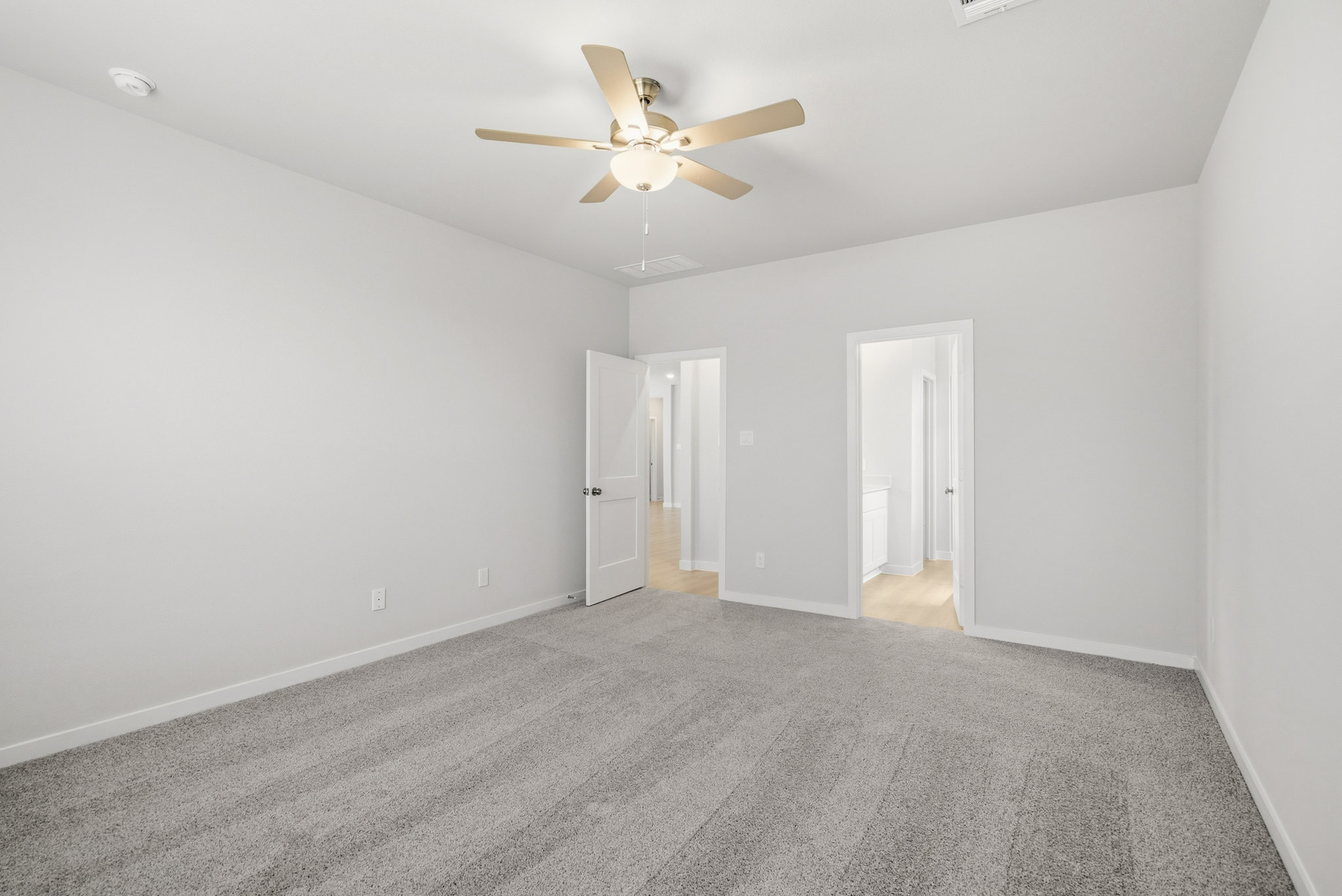 A room with a ceiling fan and a carpet.