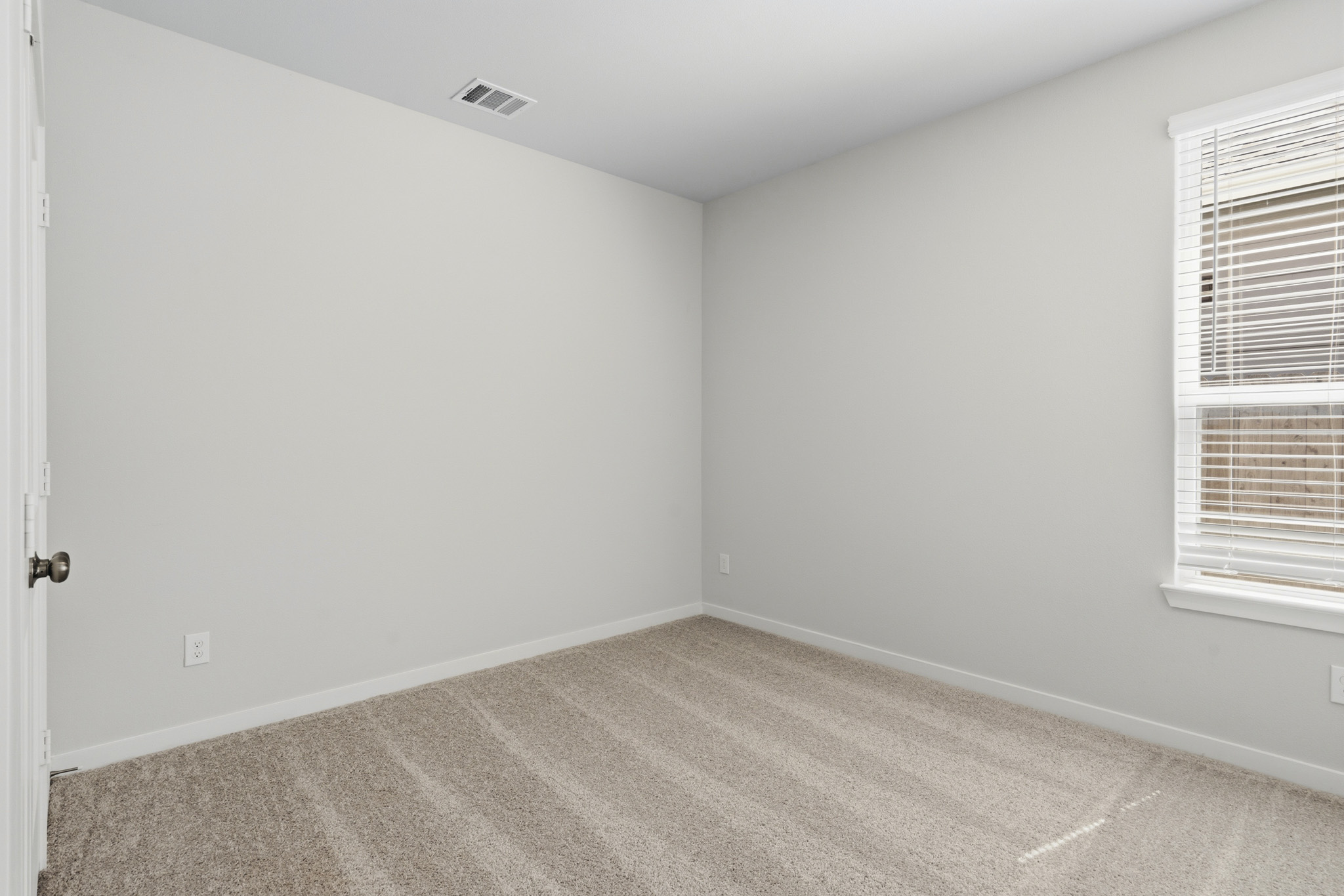 A room with a carpet and a window.