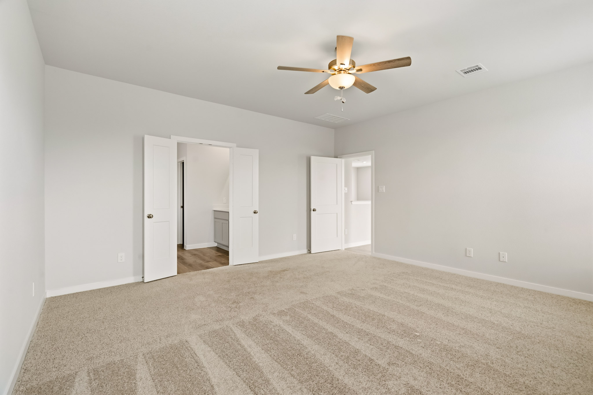 A room with a ceiling fan and a carpet.