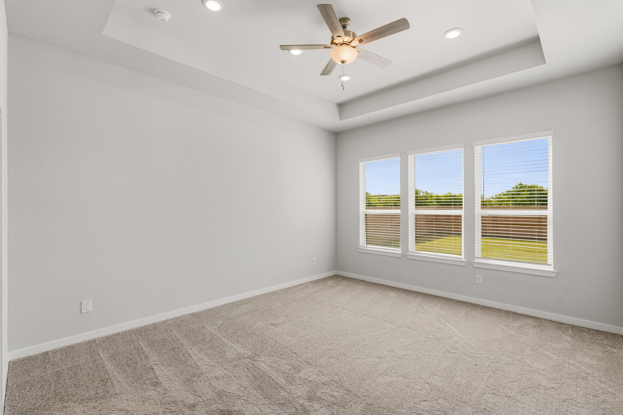 A room with a ceiling fan and a window with a view of the outside.