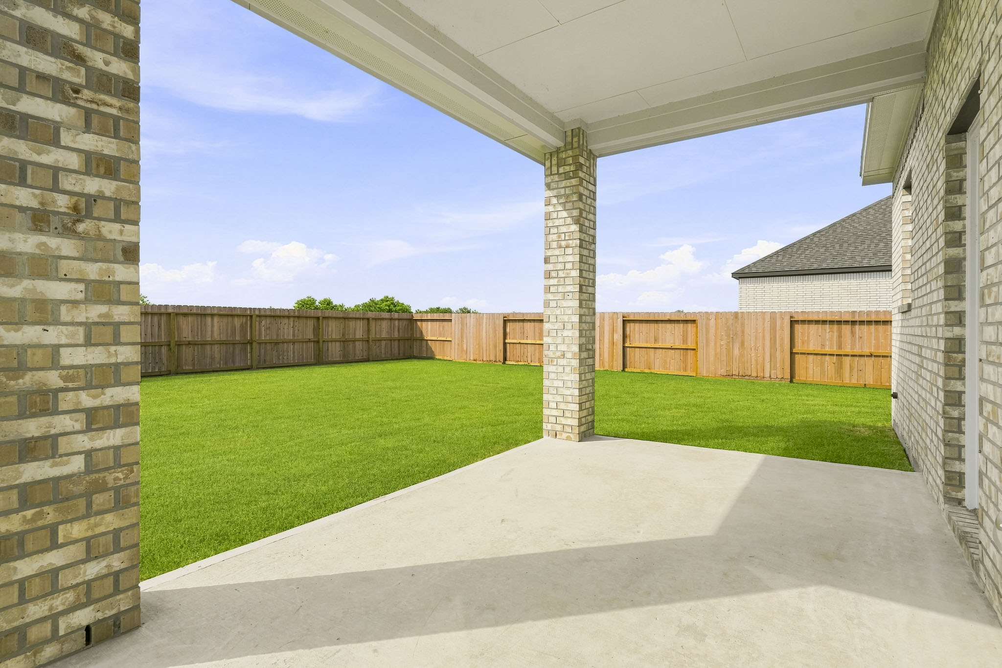 A fenced in yard with a brick wall and a brick building.