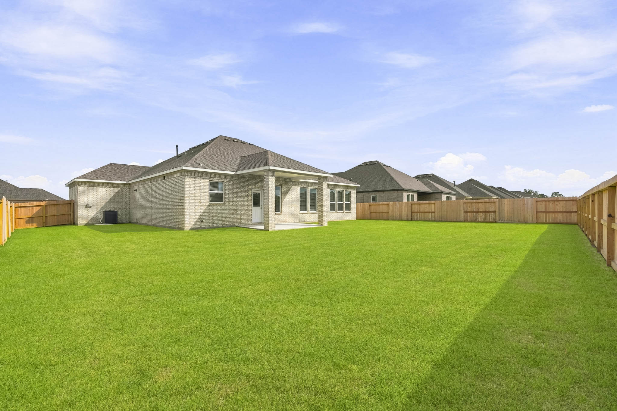 A large green lawn with a fence and a house in the background.