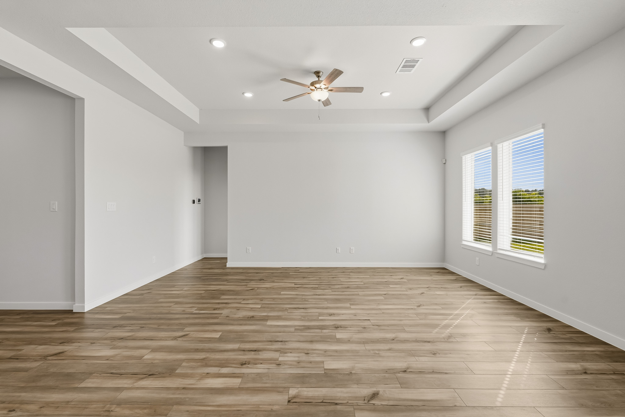A room with a wood floor and a ceiling fan.