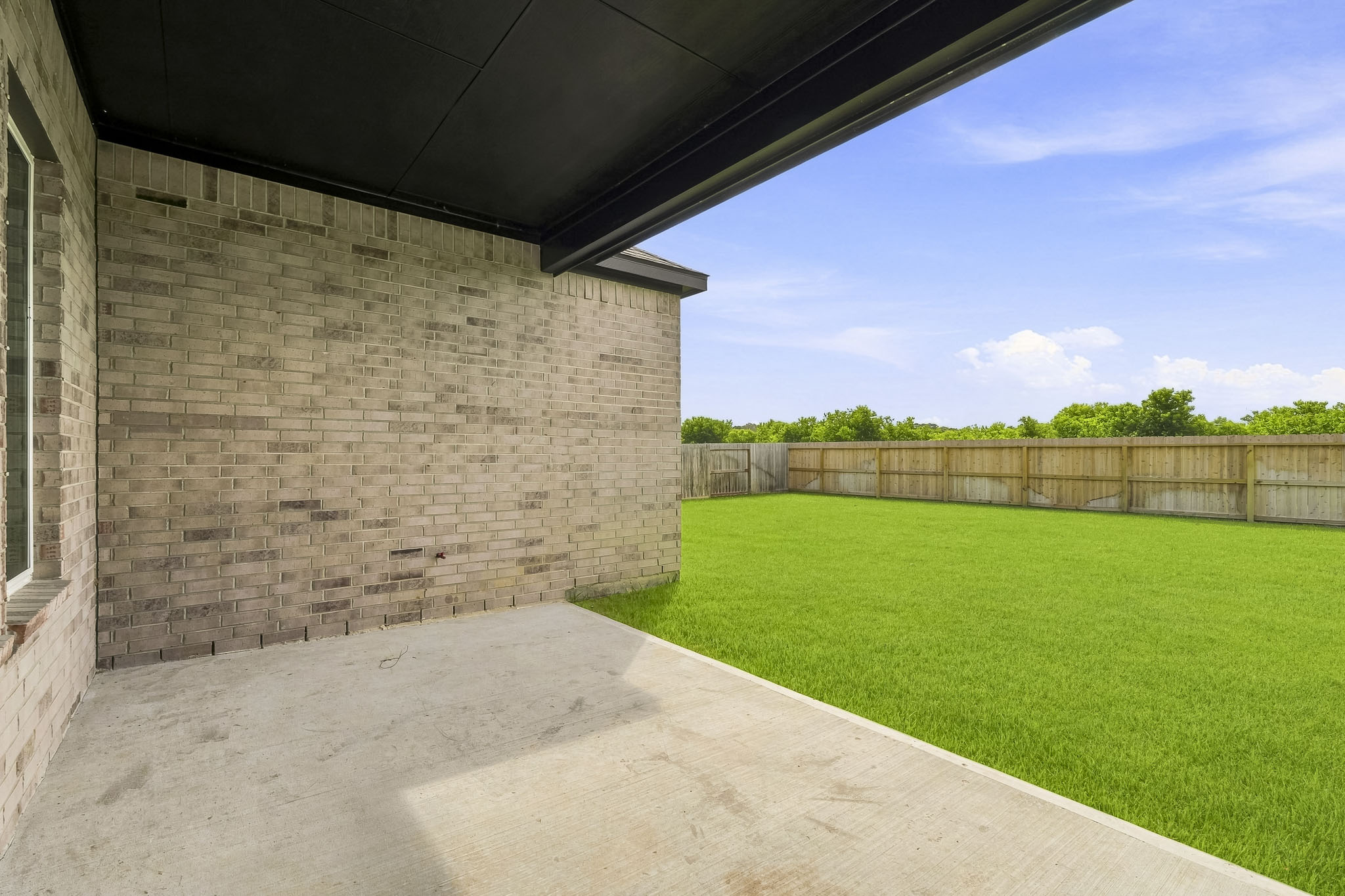 A concrete walkway next to a grass field.