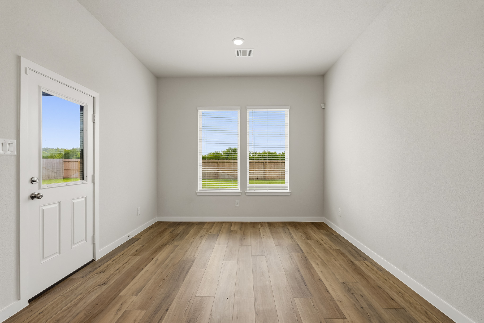 A room with a wood floor and a white door with a window.