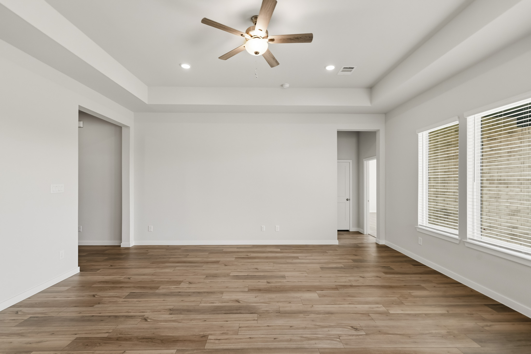 A room with a wood floor and a ceiling fan.