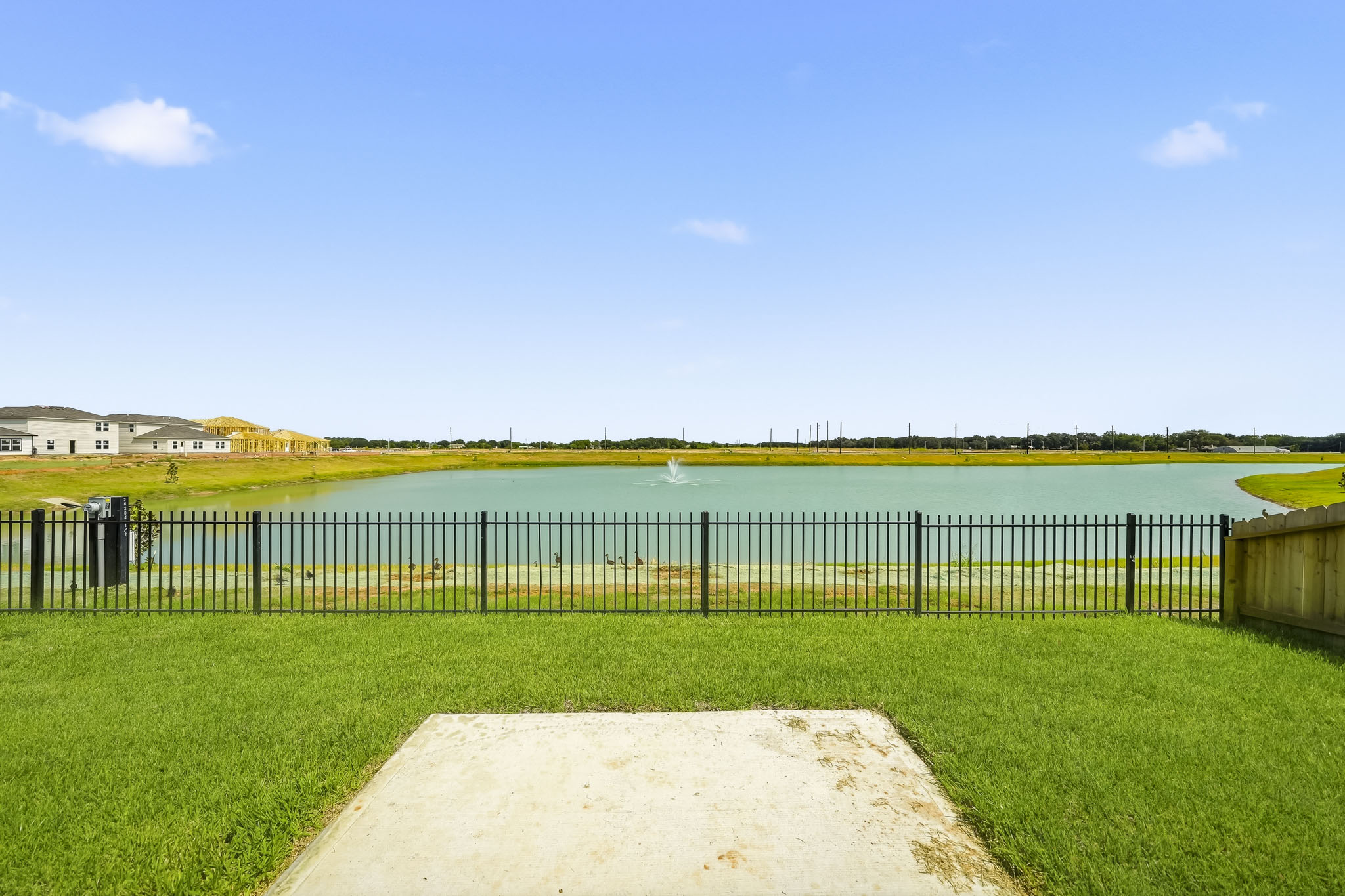 A body of water with grass and a fence around it.