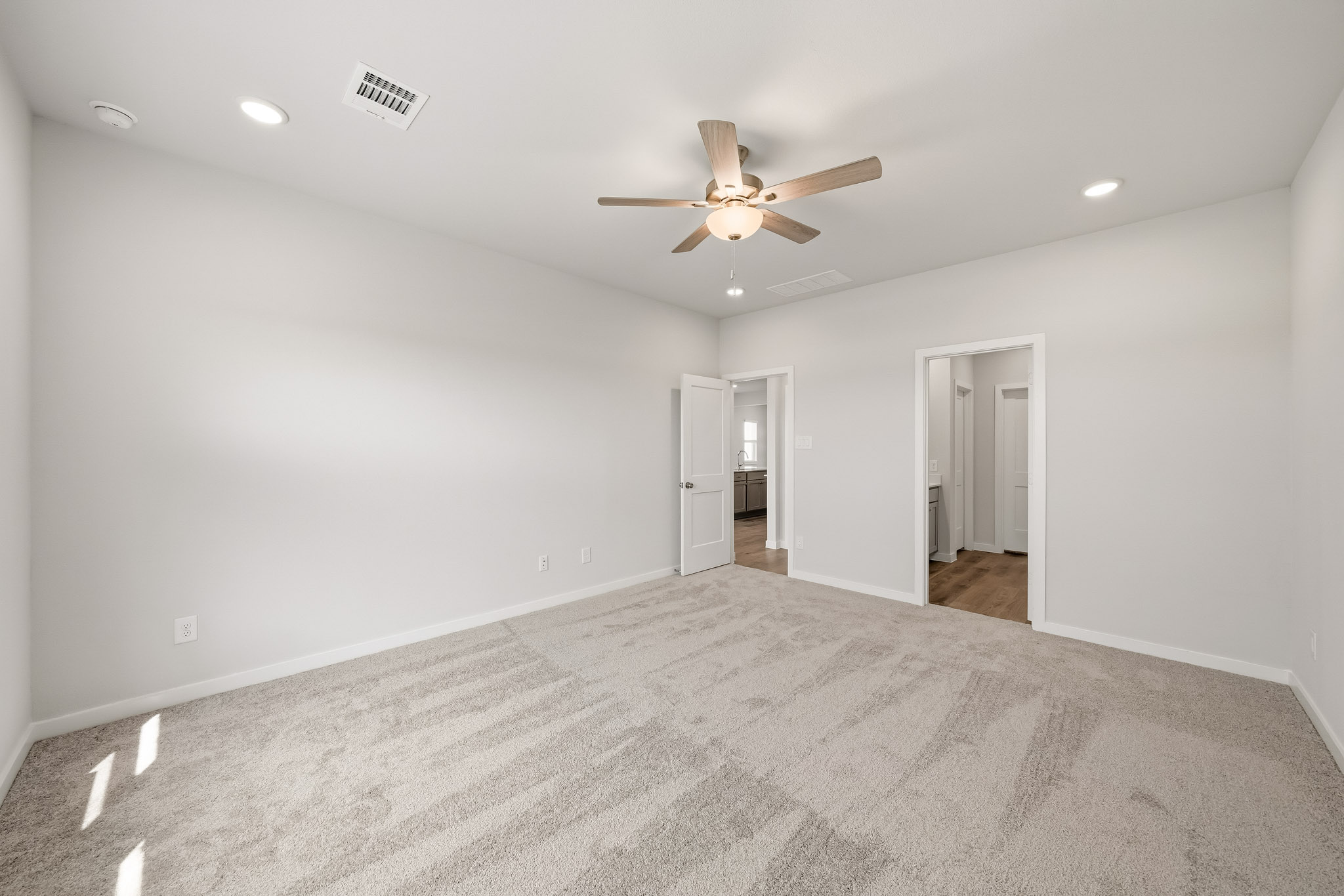 A room with a ceiling fan and a carpet.