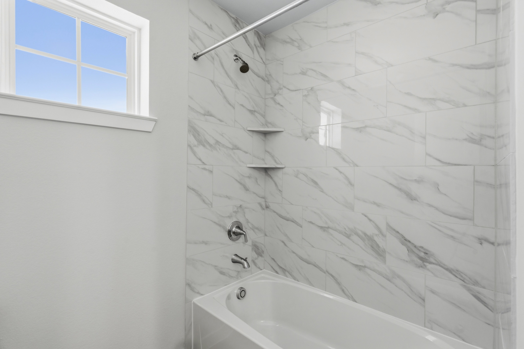 A bathroom with a bathtub and a window.