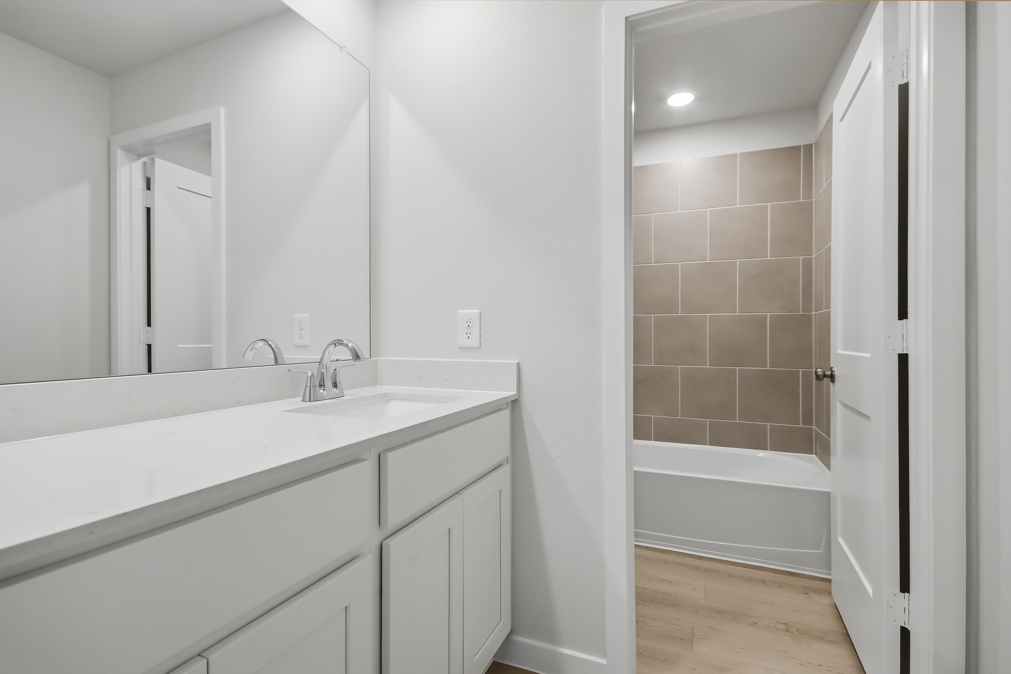 A bathroom with a tub sink and mirror.
