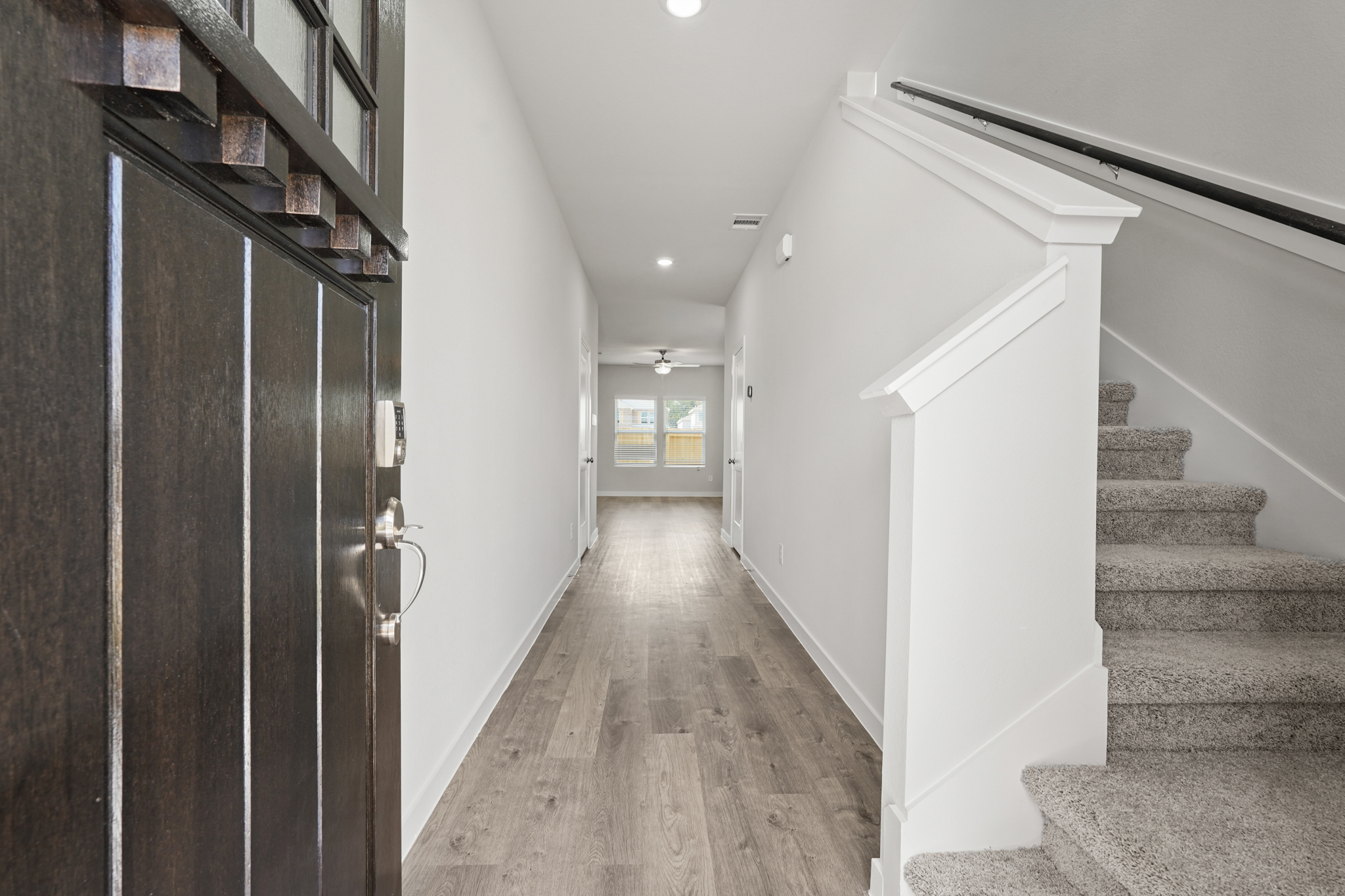 A hallway with a wood floor and a wood staircase.