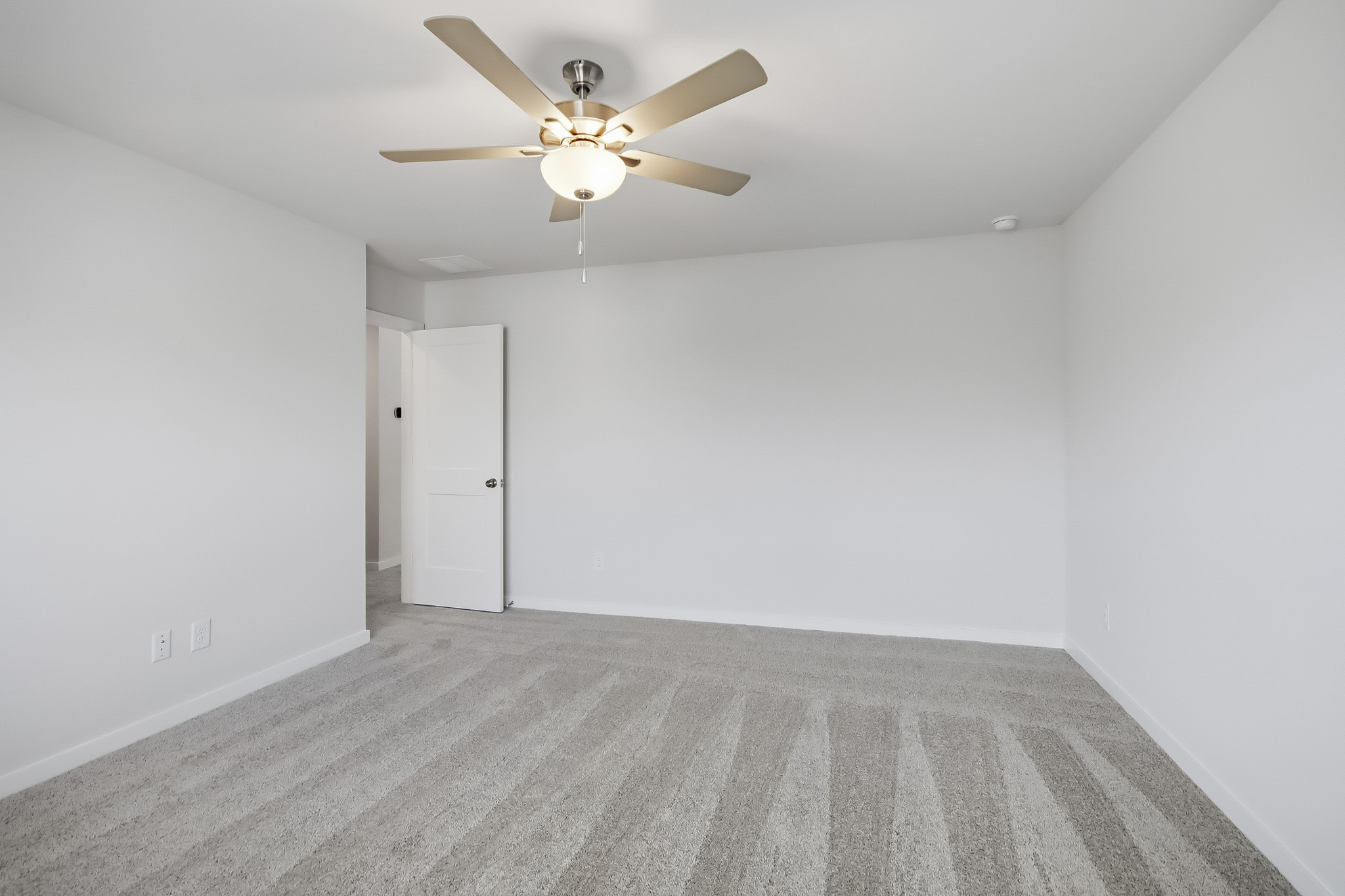 A room with a ceiling fan and a door.