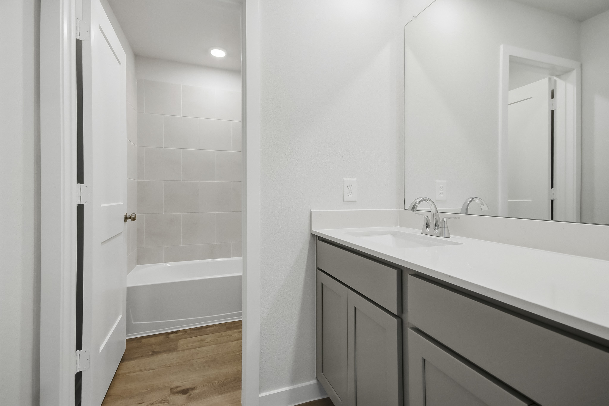 A bathroom with a tub sink and cabinets.