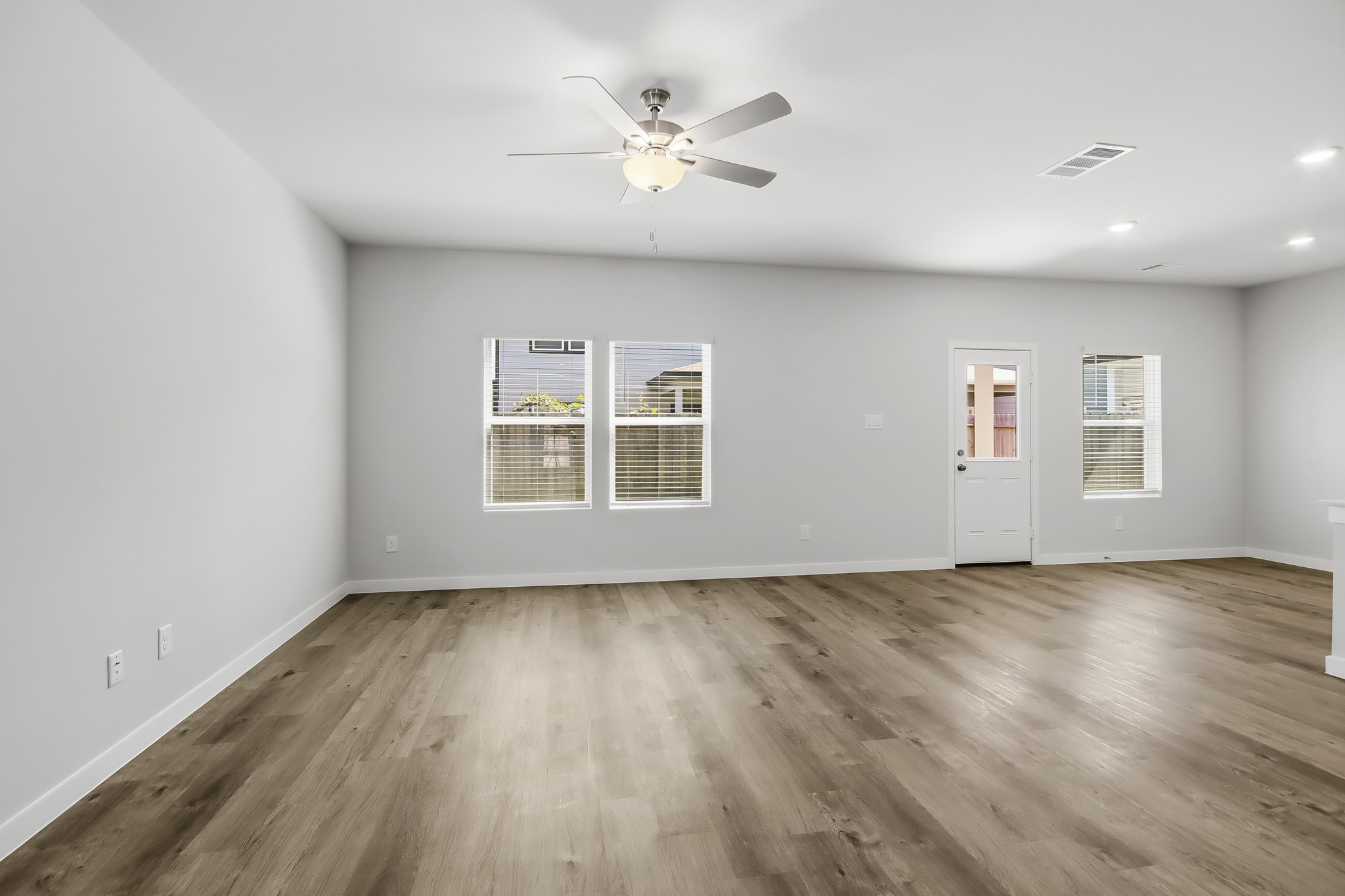 A room with a ceiling fan and a wood floor.