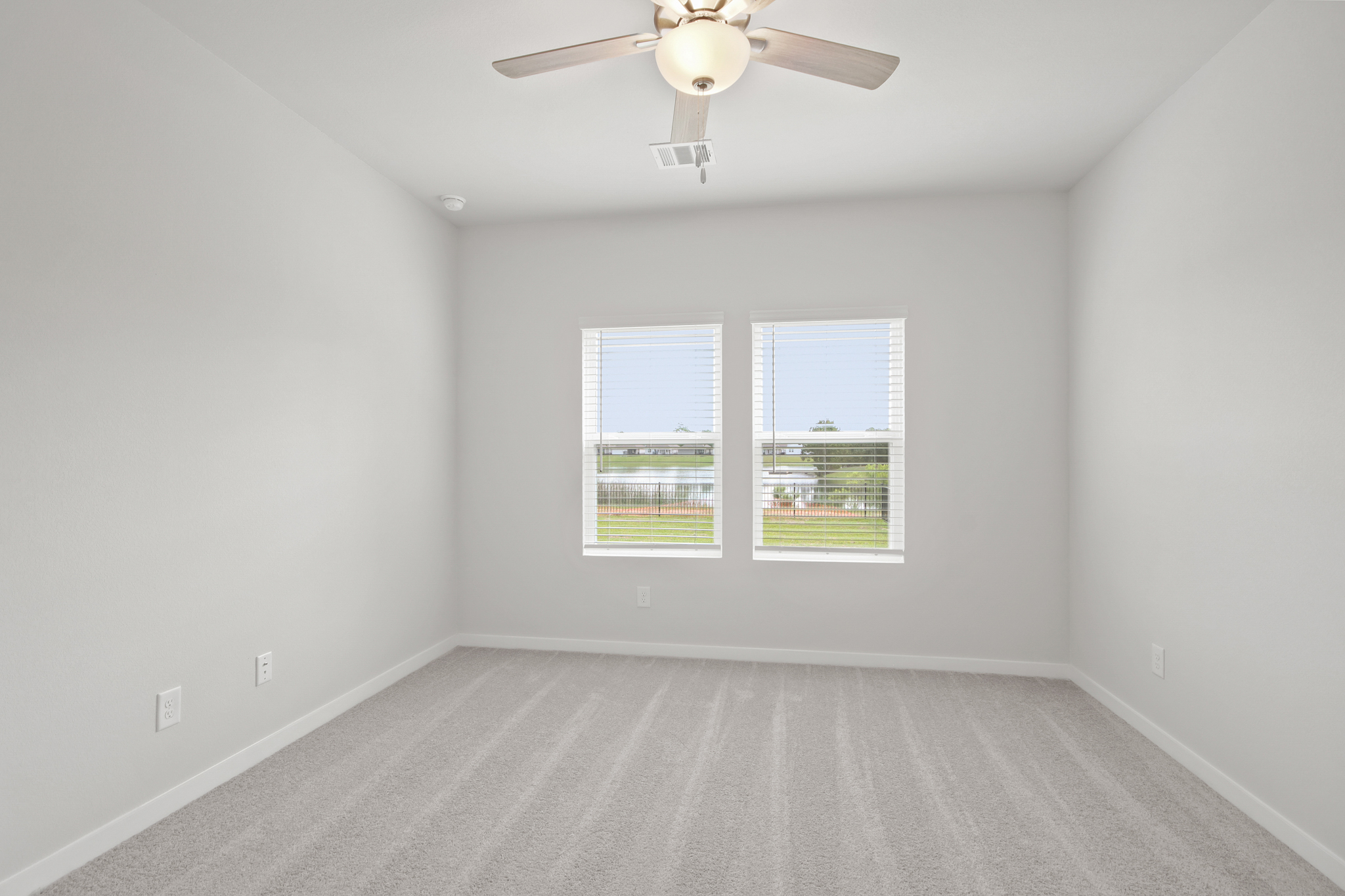 A room with a ceiling fan and a window with blinds.
