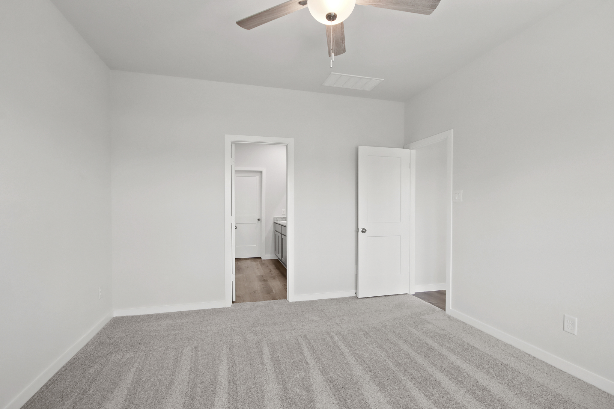 A room with a ceiling fan and a door.