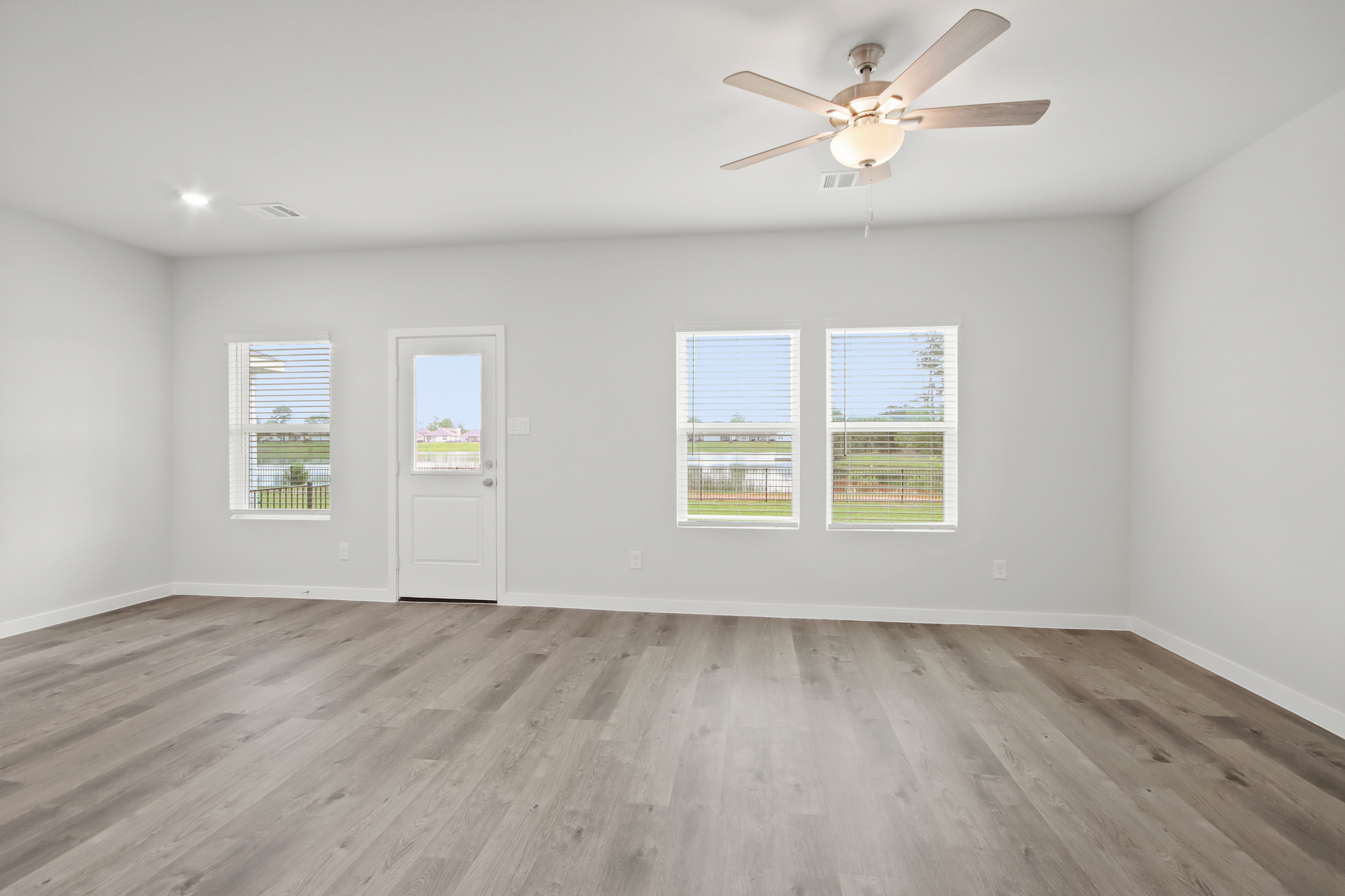 A room with a ceiling fan and a wood floor.