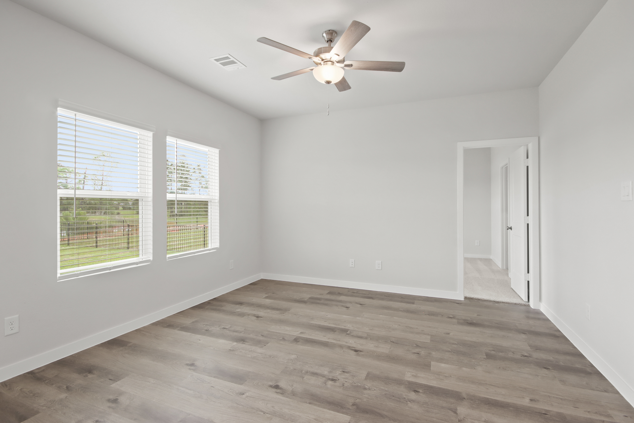 A room with a ceiling fan and a wood floor.