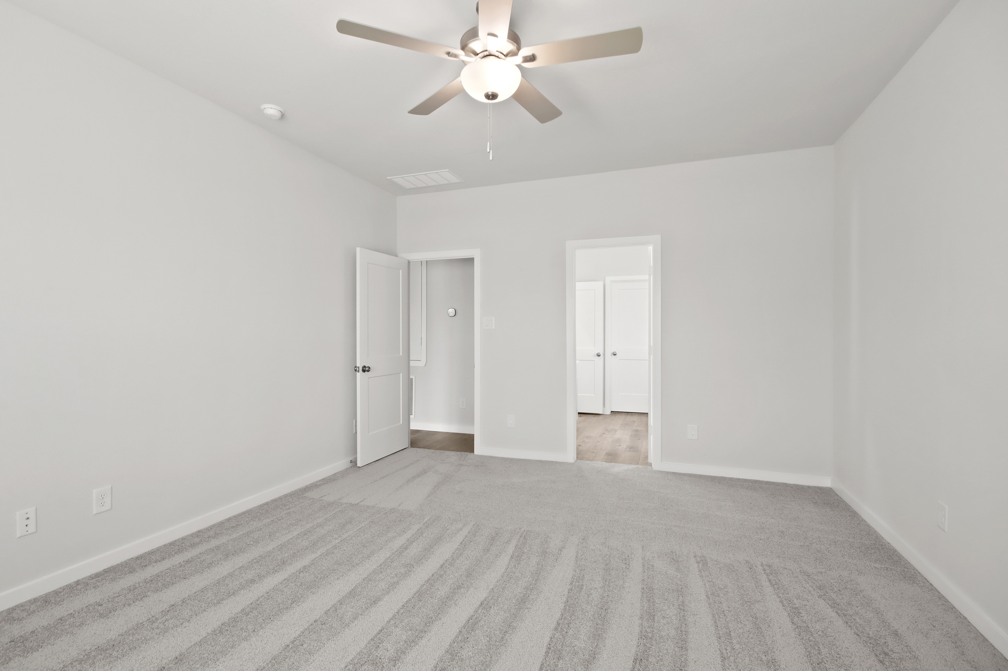 A room with a ceiling fan and white walls.
