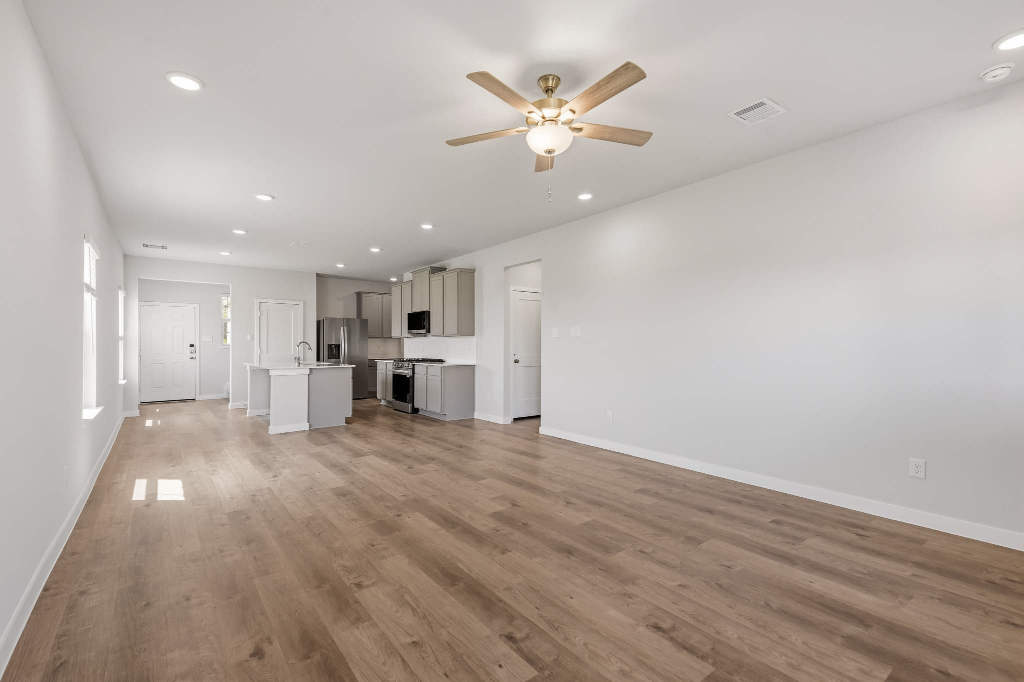 A large empty room with a ceiling fan and a wood floor.