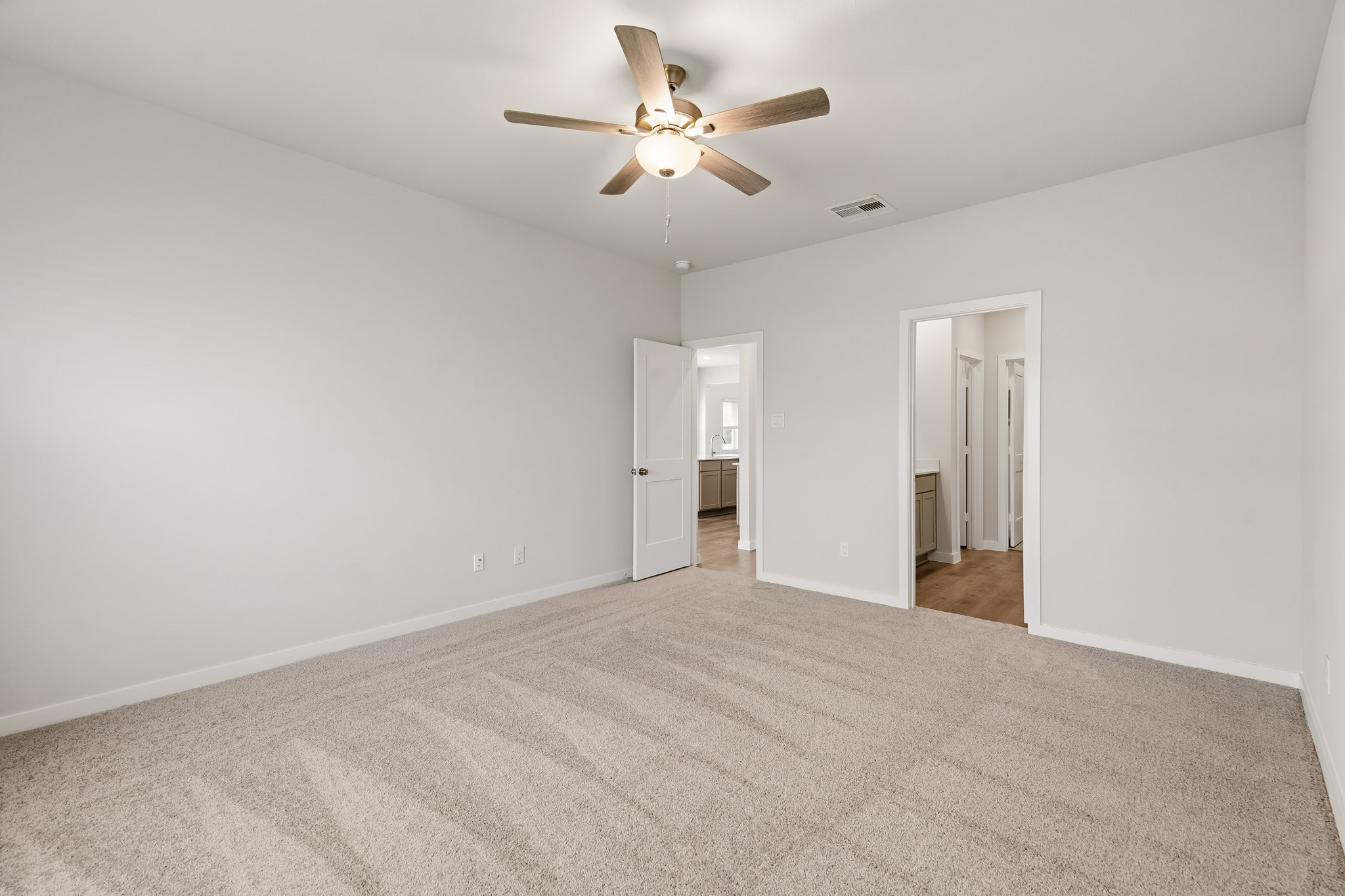 A room with a ceiling fan and a carpet.