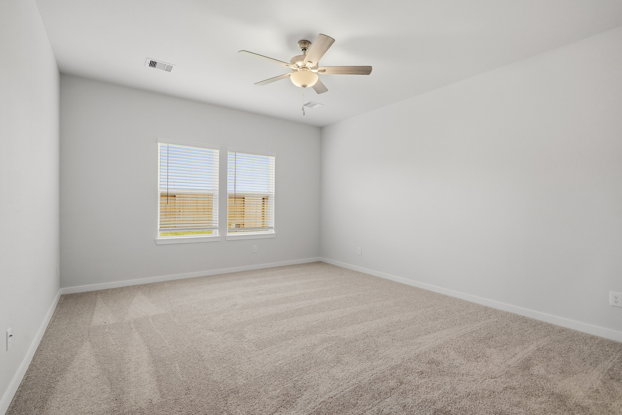 A room with a ceiling fan and a carpet.