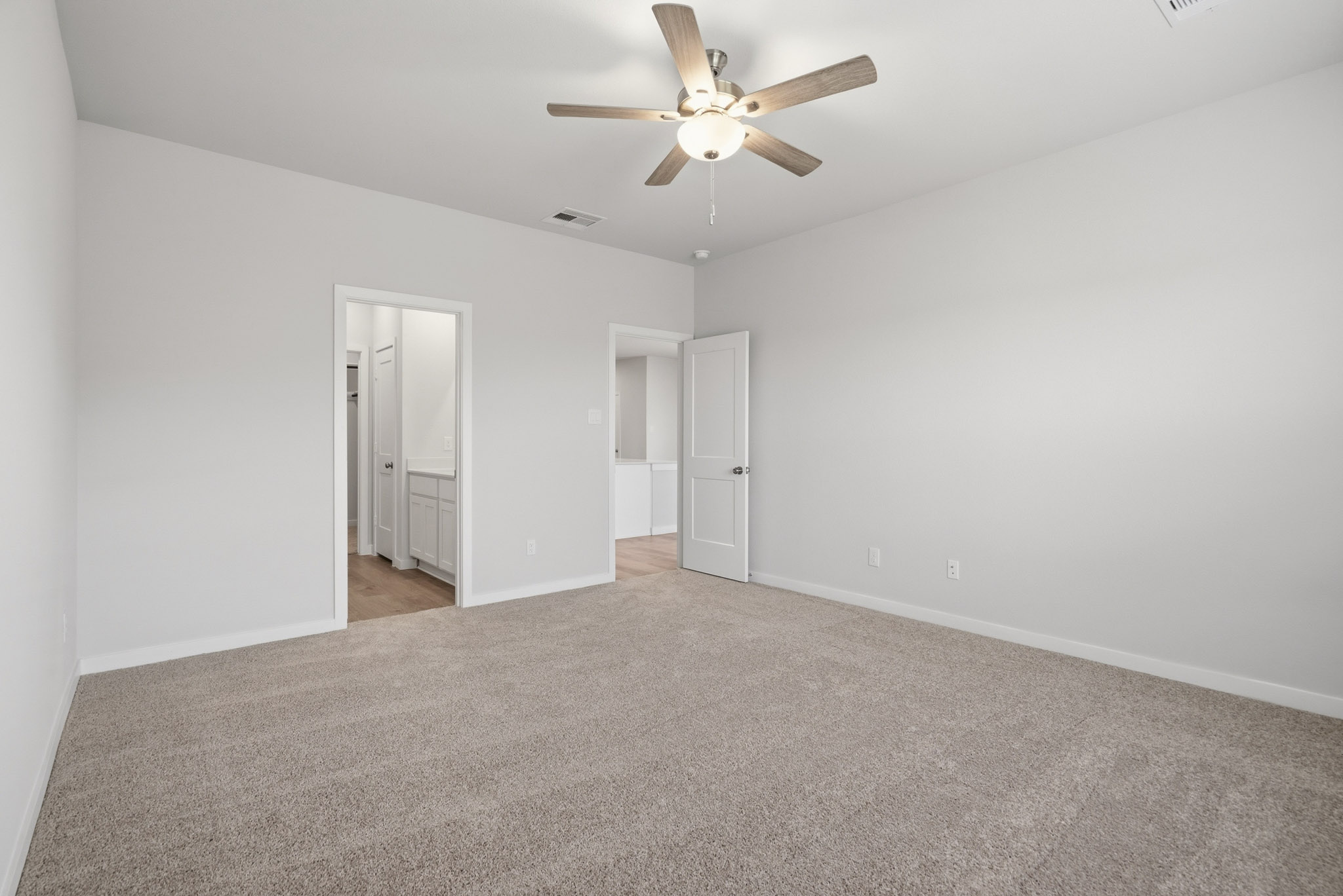 A room with a ceiling fan and a carpet.