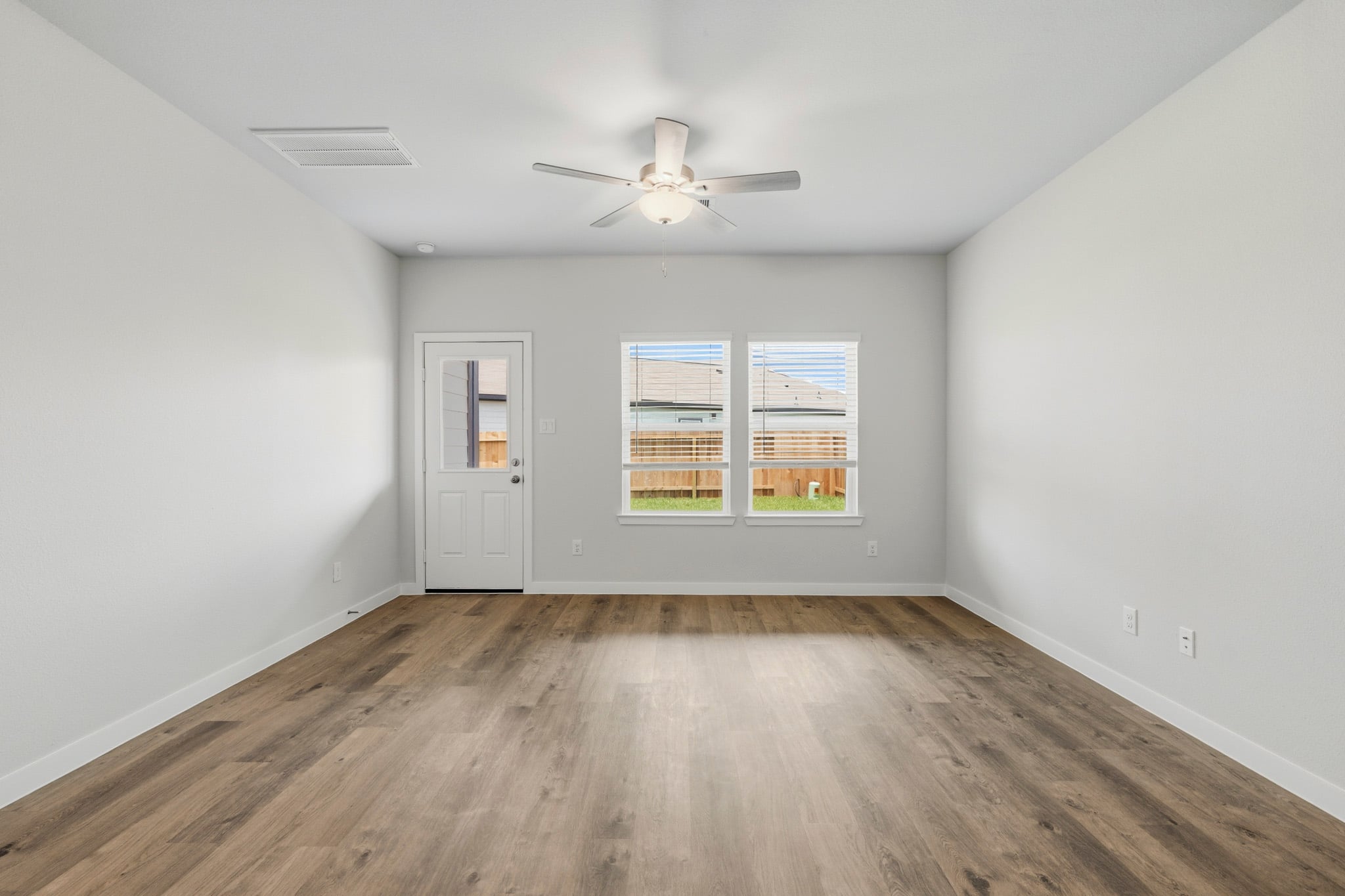 A room with a ceiling fan and a wood floor.
