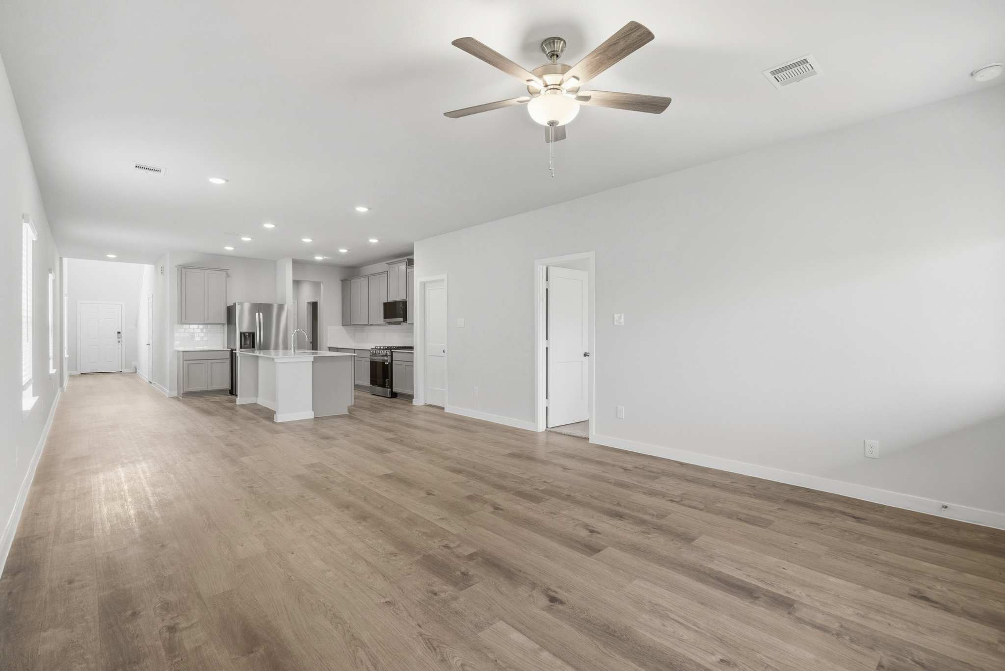 A large empty room with a ceiling fan and a wood floor.