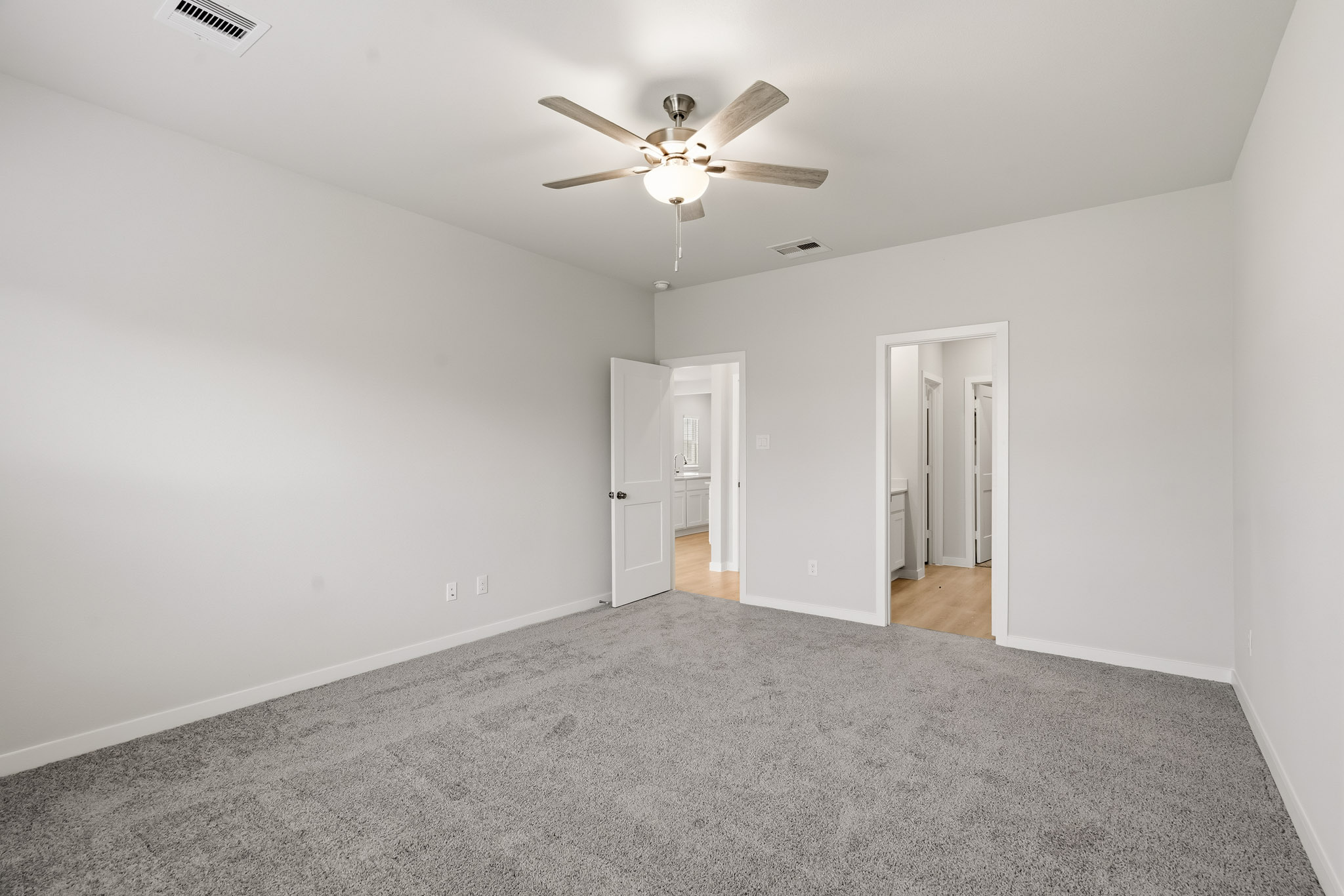A room with a ceiling fan and a carpet.