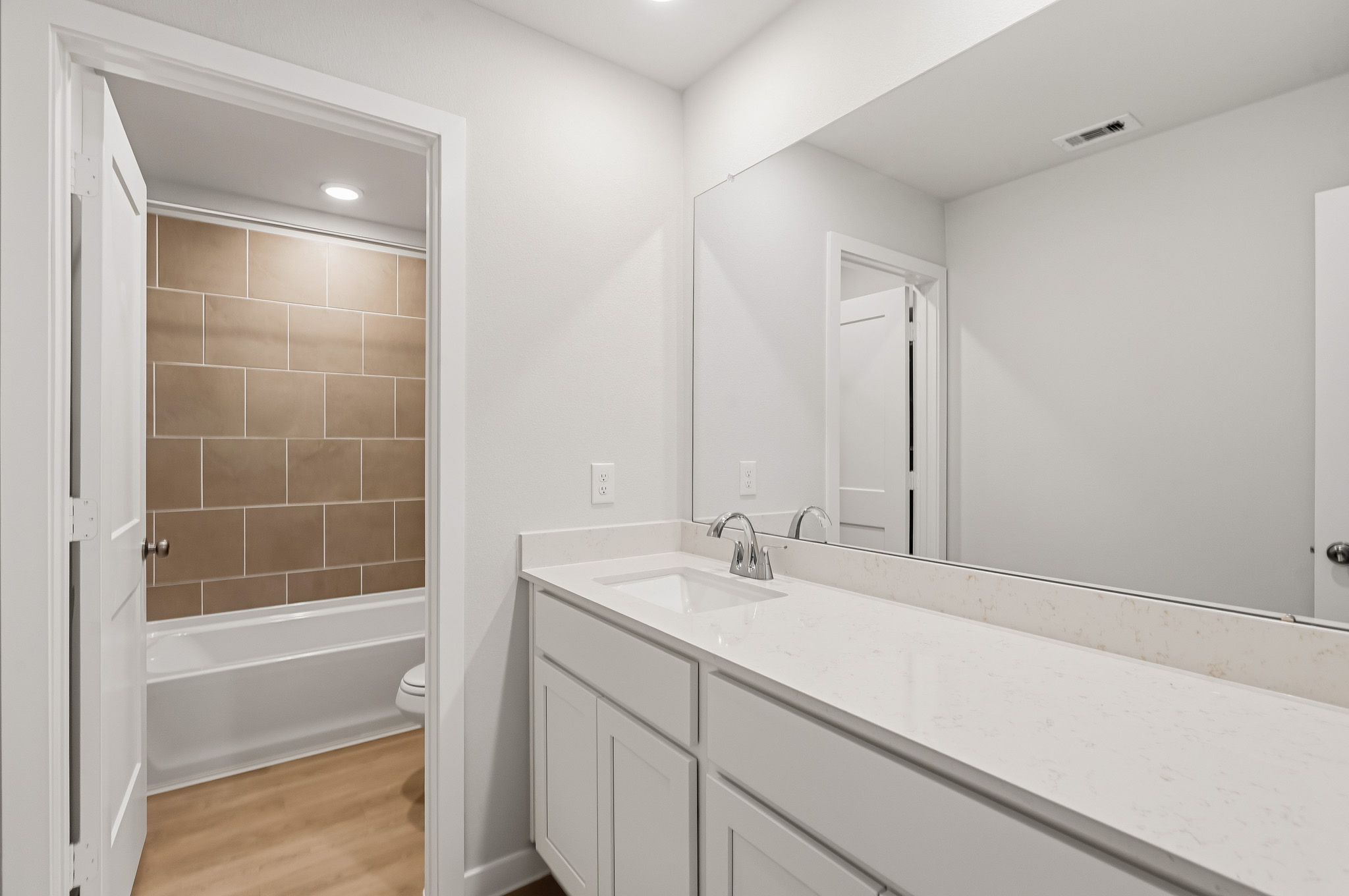 A bathroom with a tub sink and mirror.